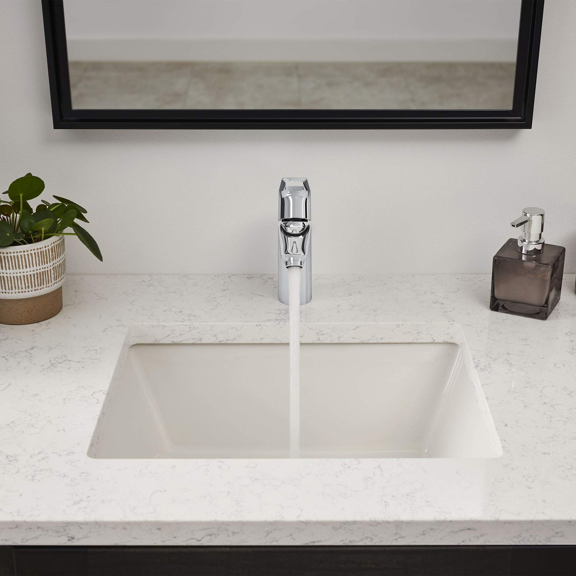 Chrome single-handle bathroom faucet with tall spout mounted on marble countertop above white undermount sink.