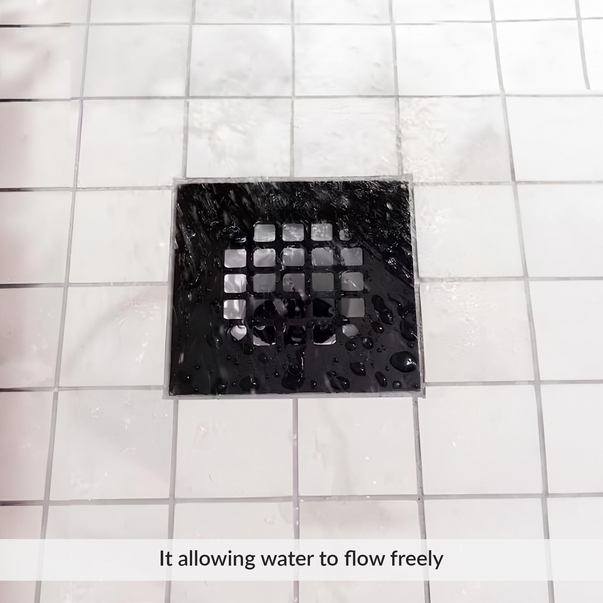 Matte black square shower strainer with grid pattern installed in white tile floor.