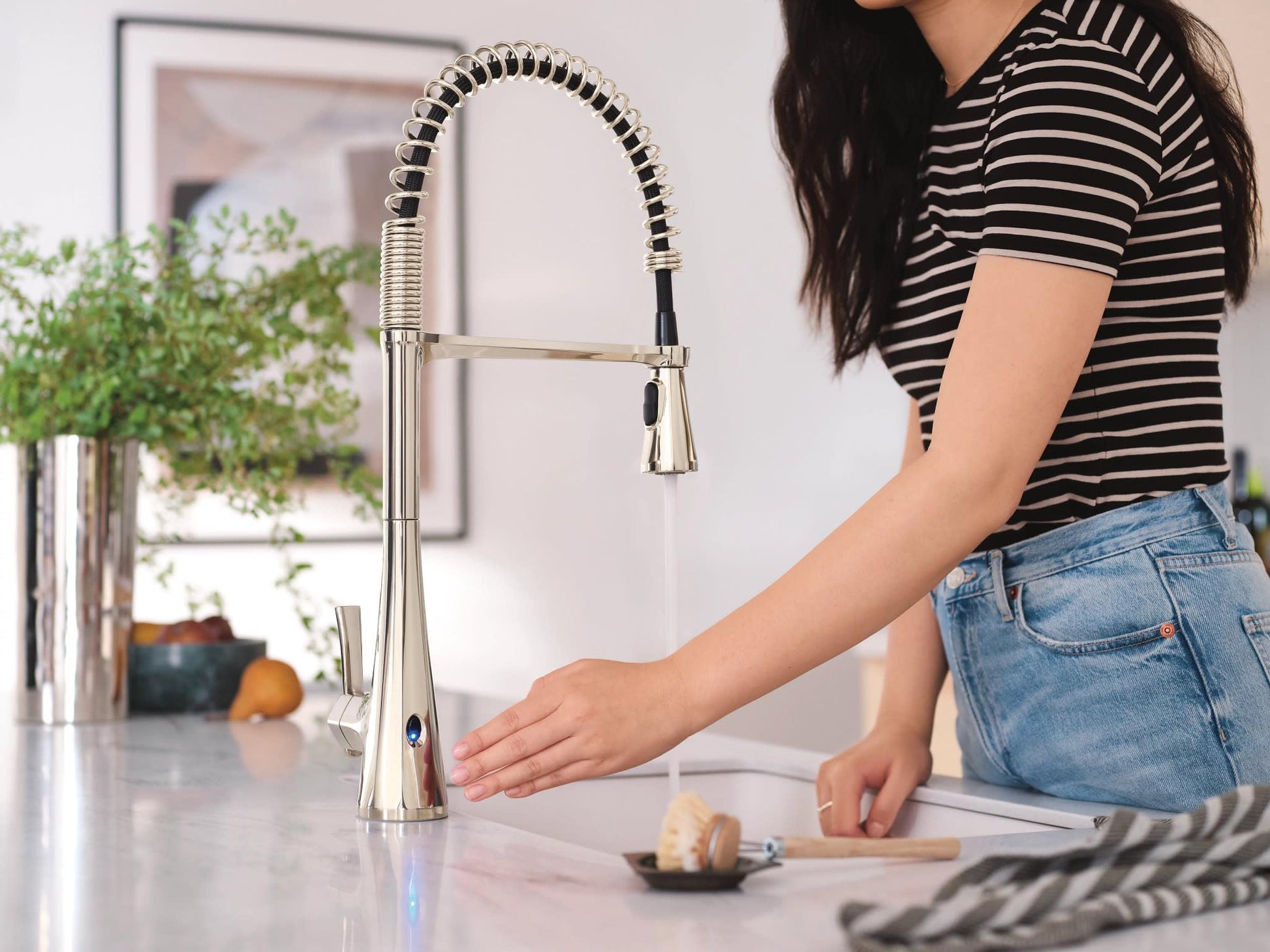 Polished nickel high arc kitchen faucet with pulldown sprayer and wave motion sensor mounted on white countertop.
