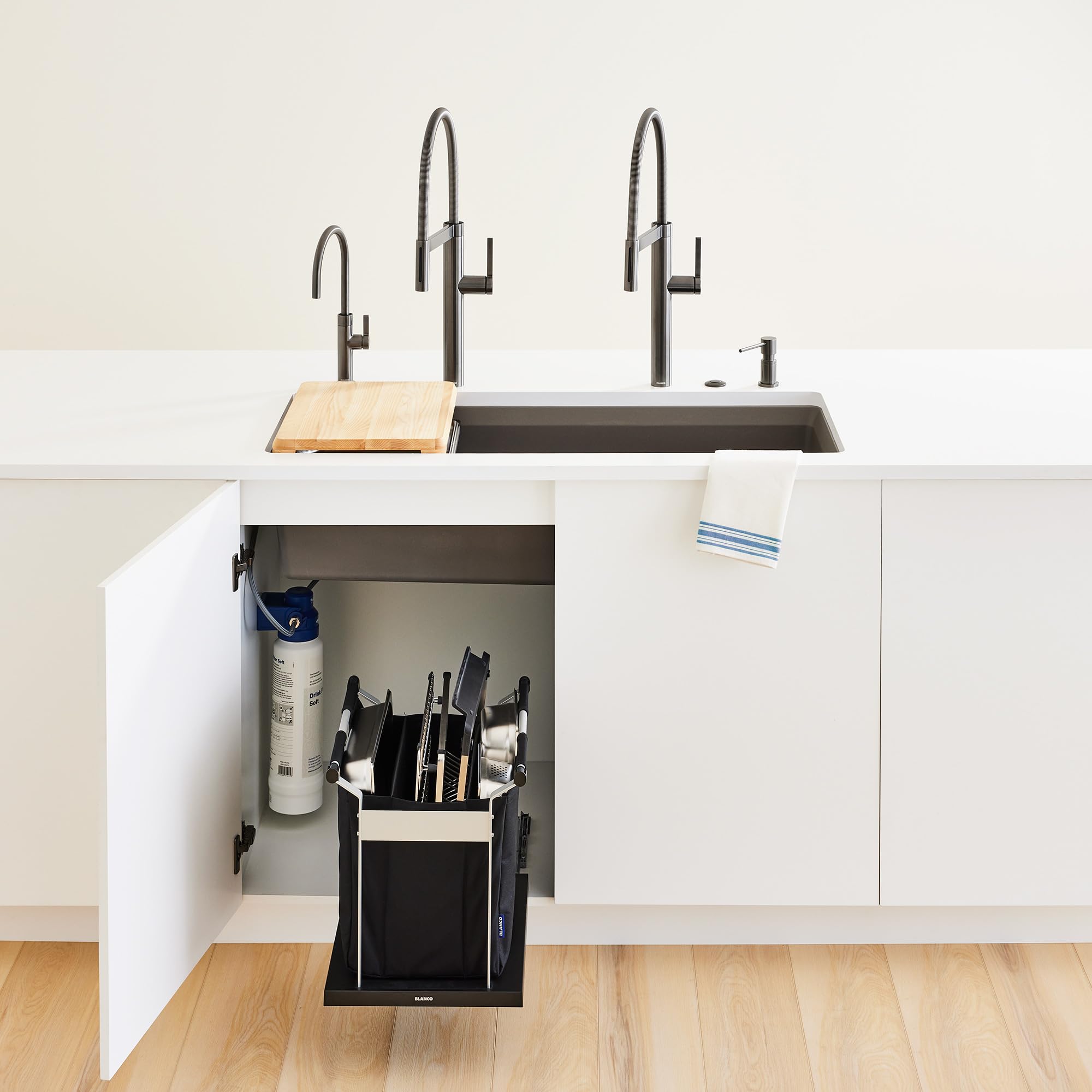 Satin dark steel beverage faucet with curved spout and lever handle mounted above kitchen sink.