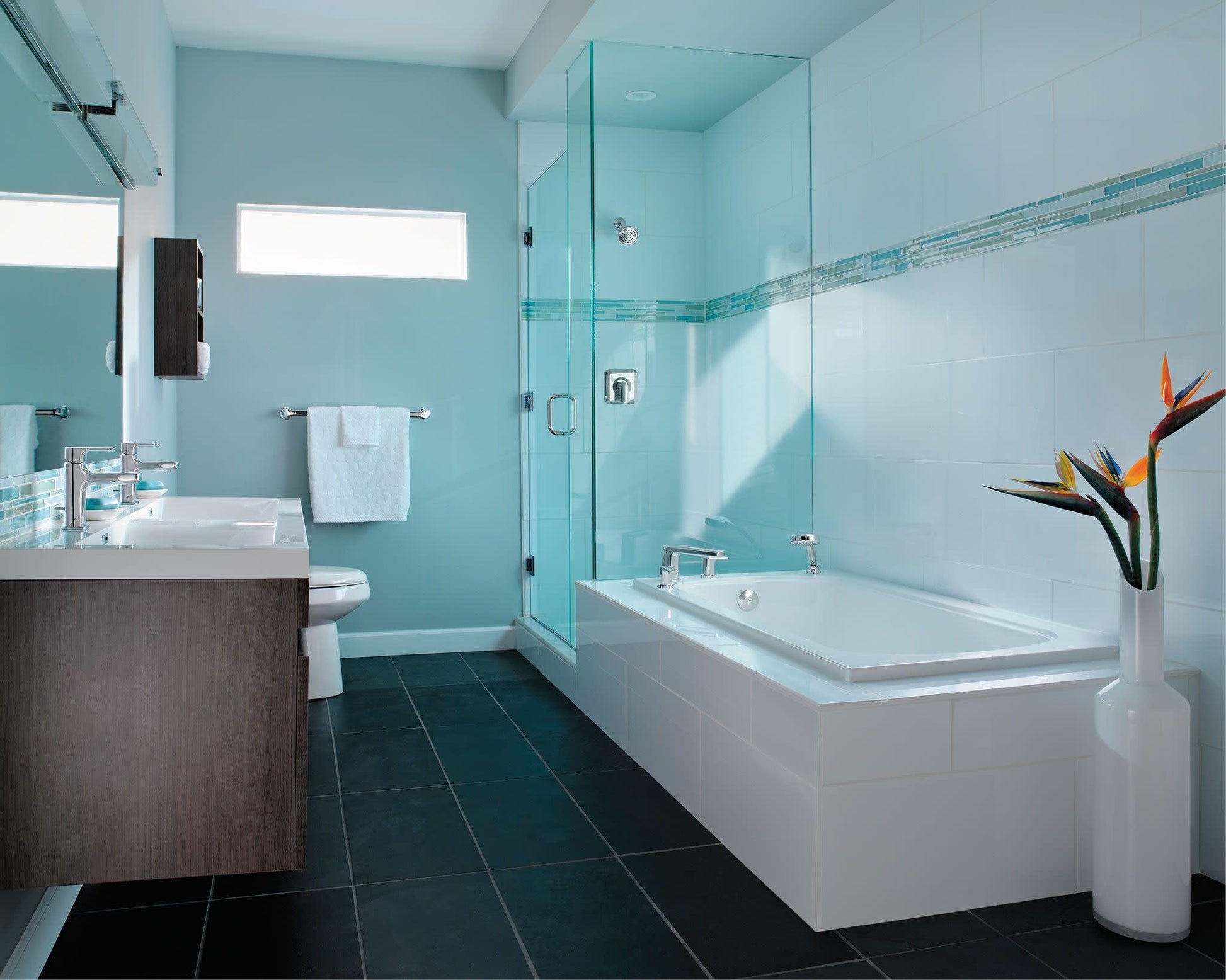 Chrome single-handle bathroom faucet installed on vanity sink in modern bathroom with glass shower enclosure.