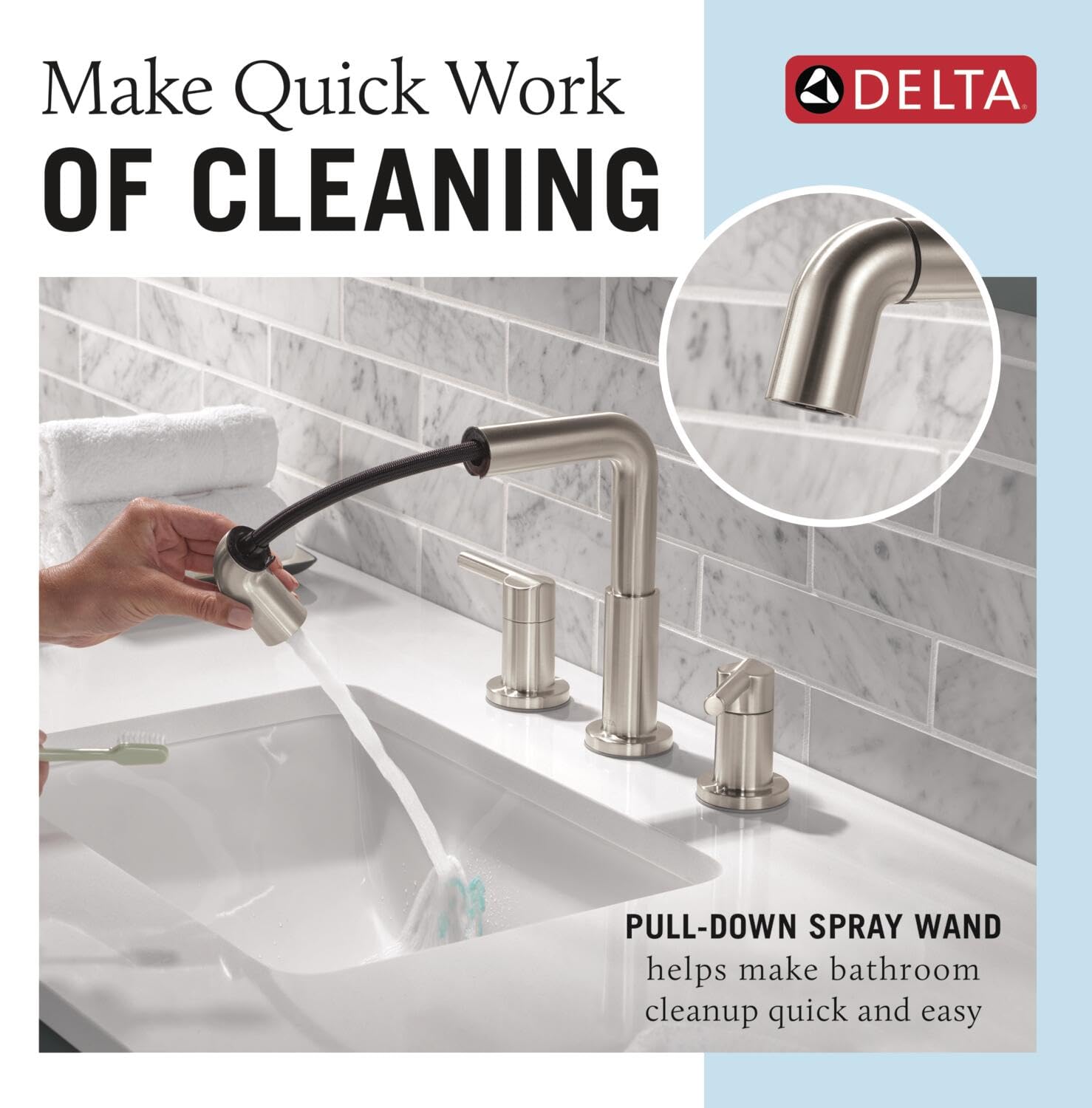 Stainless steel two-handle widespread bathroom faucet with pull-down spray wand over white sink and marble tile backsplash.