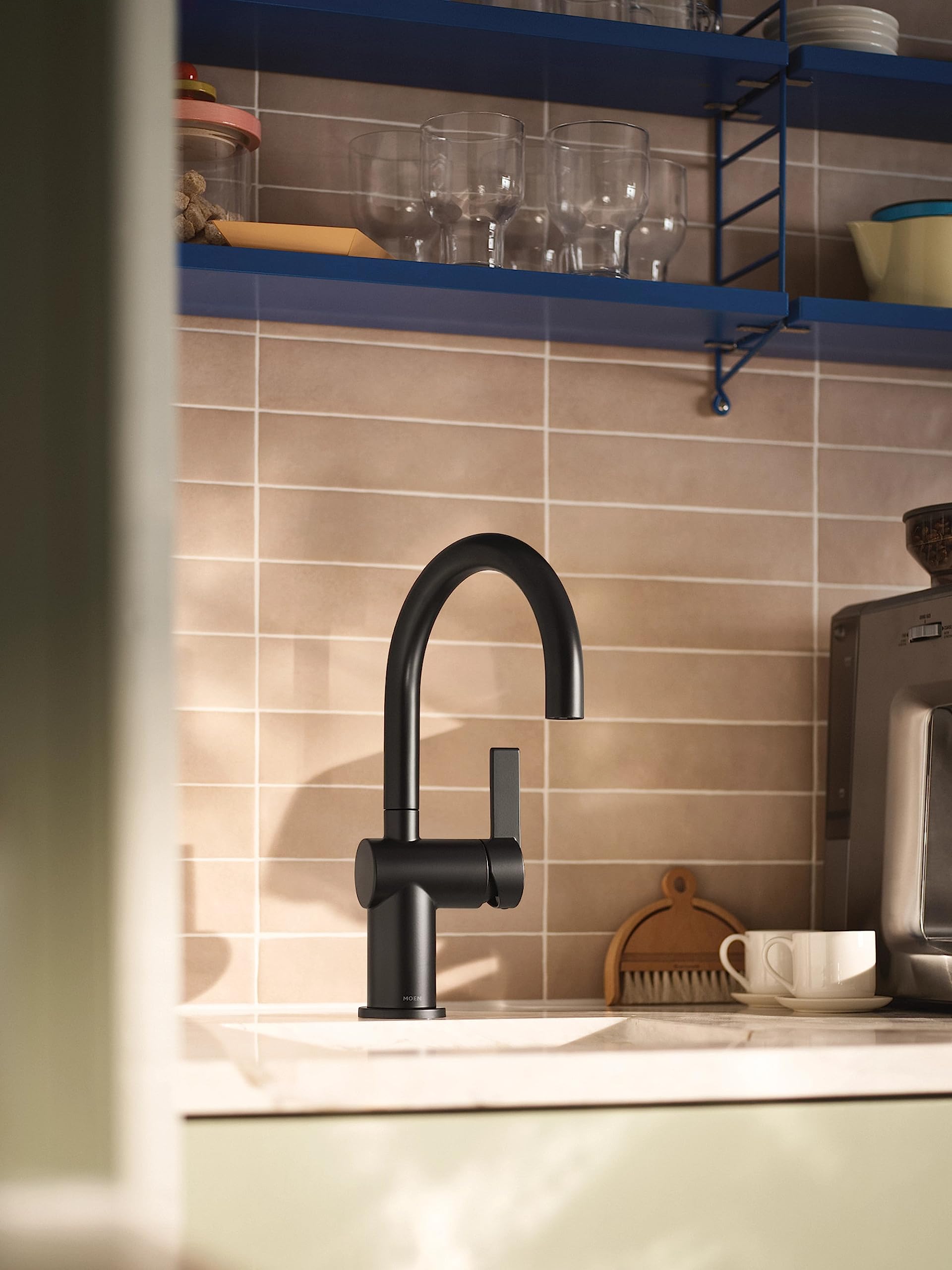 Matte black single-handle bar faucet with curved spout installed on kitchen counter backsplash.