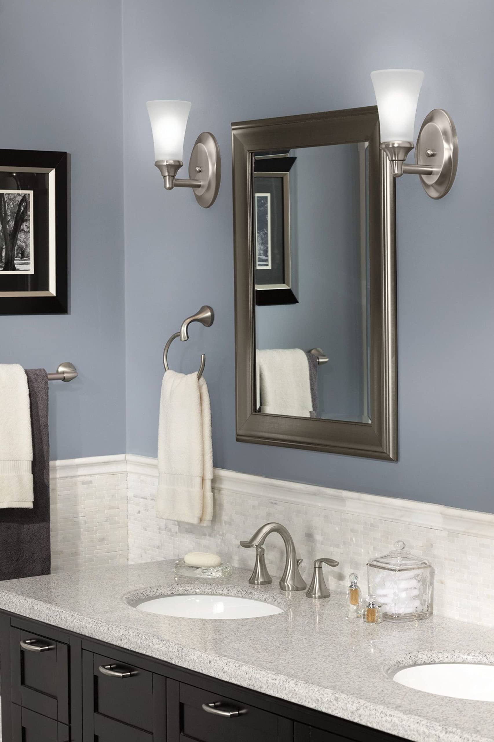 Brushed nickel wall-mount towel ring holding white towel in bathroom setting.