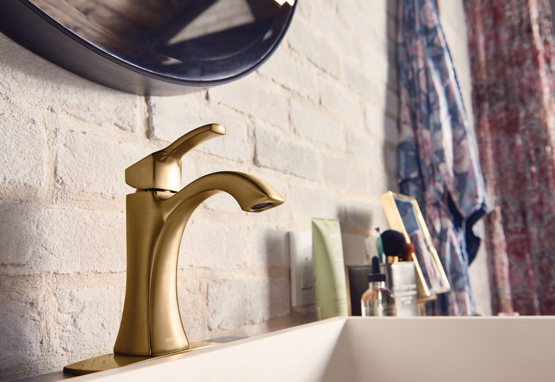 Gold single-handle bathroom faucet with high arc spout and lever handle on white sink.