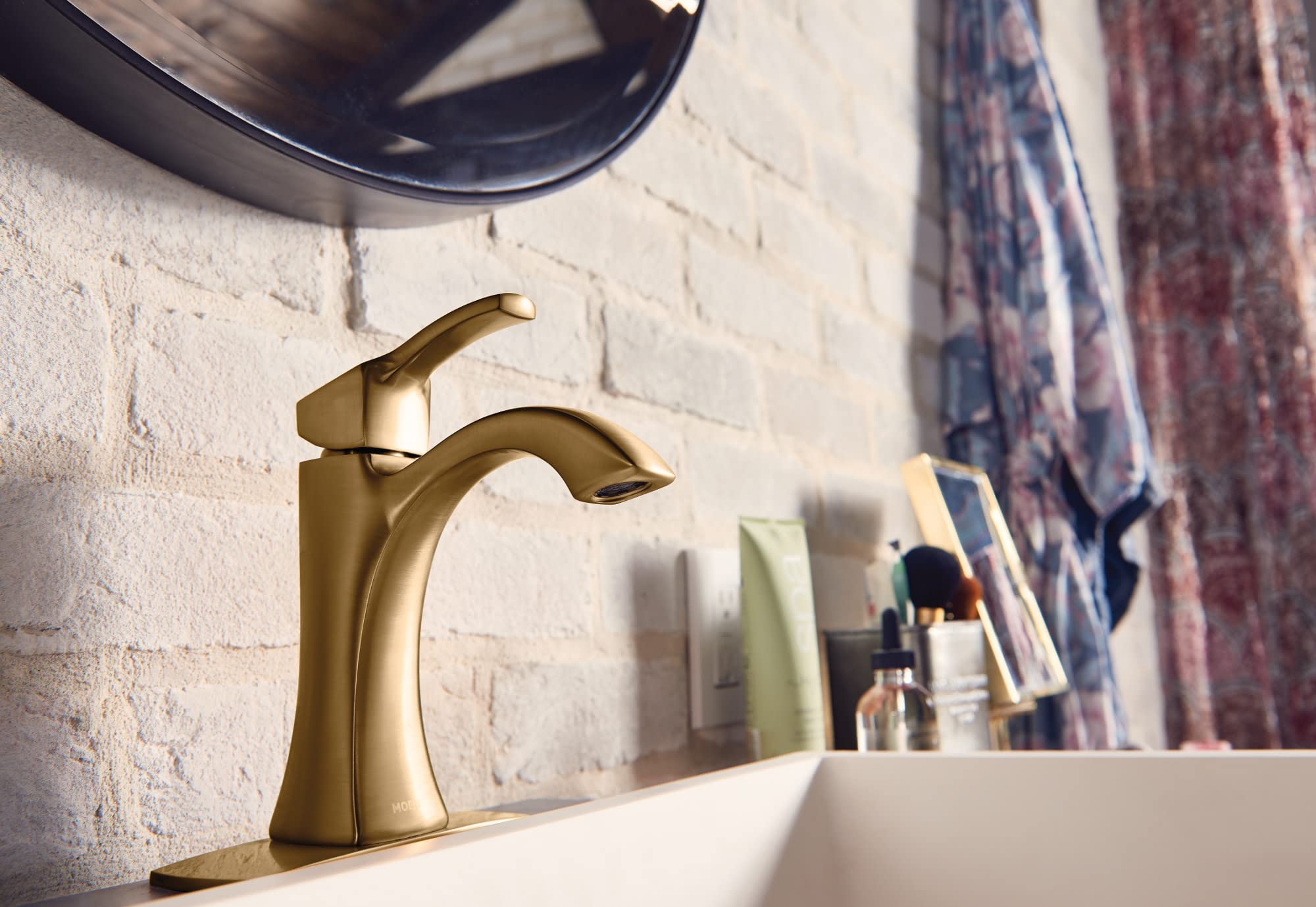 Gold single-handle bathroom faucet with high arc spout and lever handle on white sink.