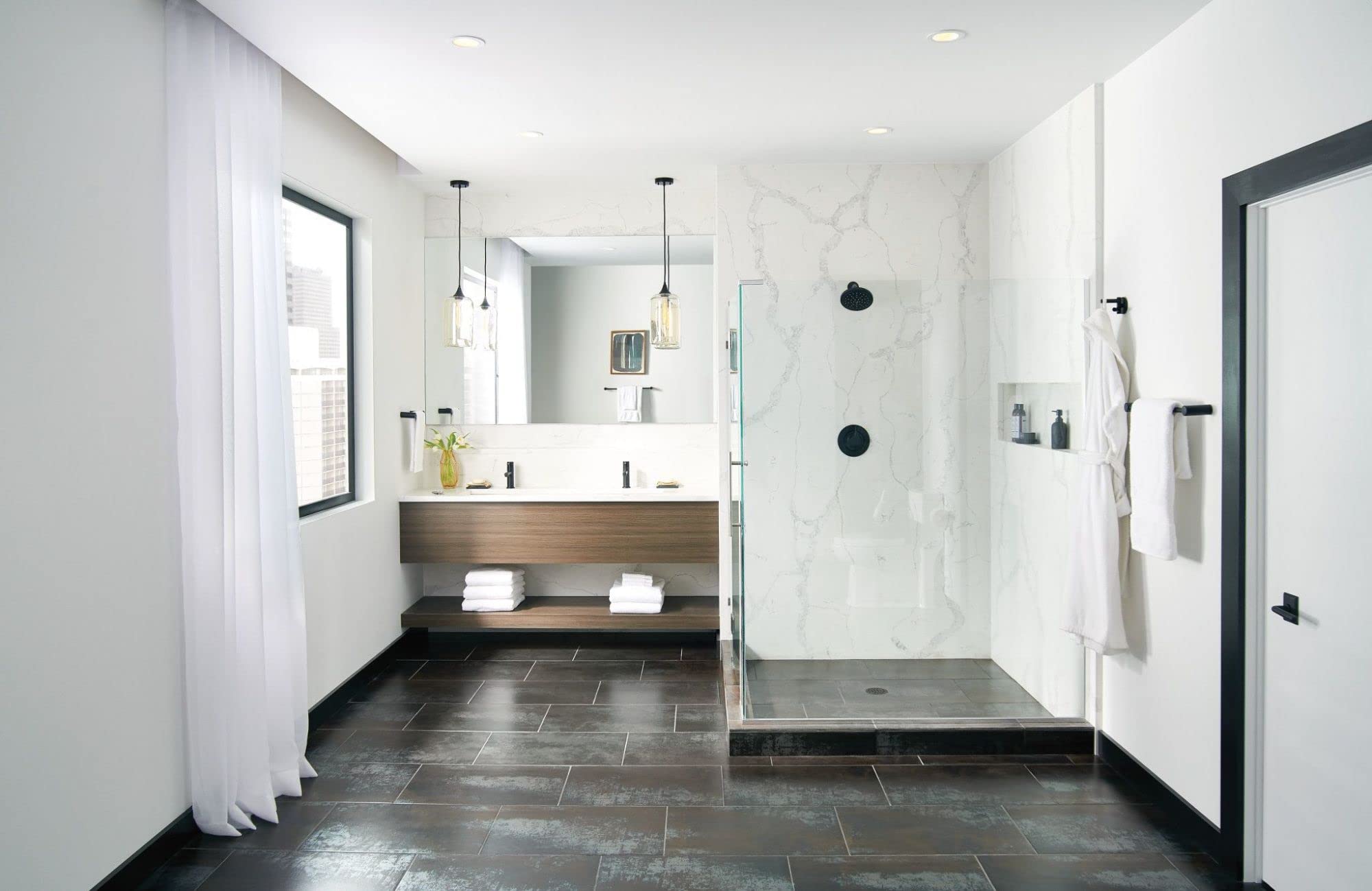 Matte black circular shower head mounted on marble shower wall in modern bathroom.