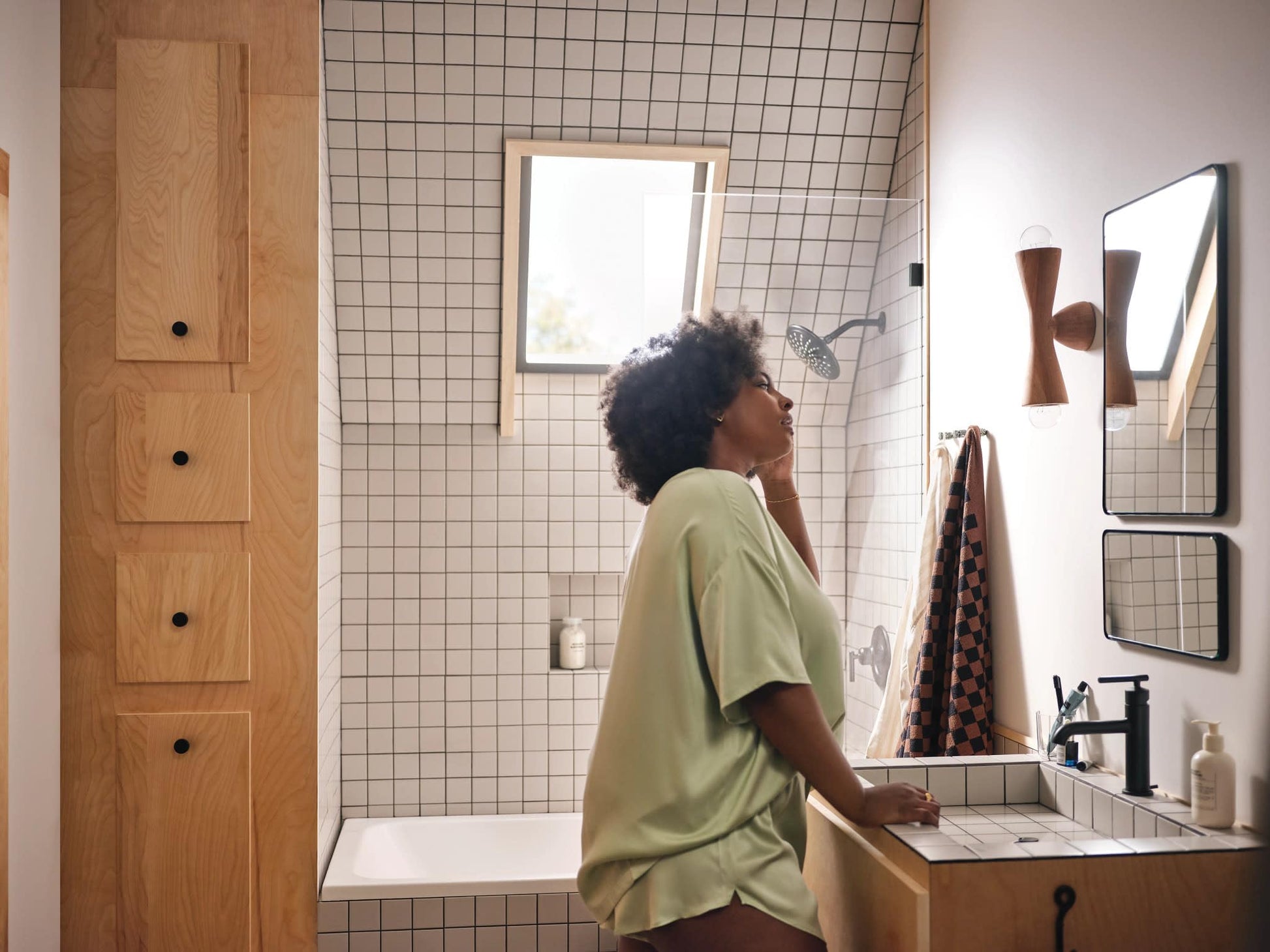 Matte black single-handle bathroom faucet with tall spout mounted on white sink in tiled bathroom.