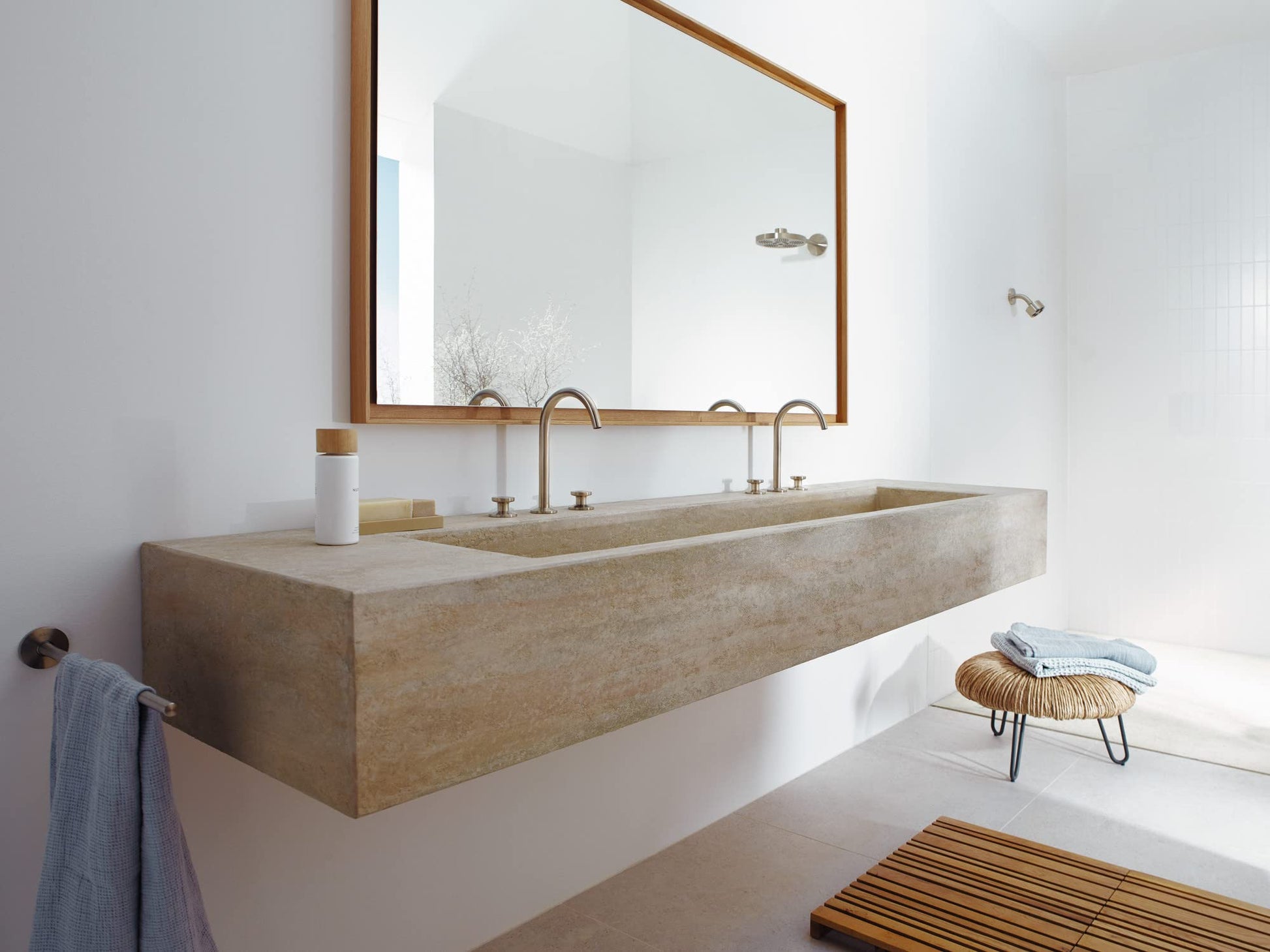 Brushed nickel single-jet shower head mounted on white bathroom wall above concrete sink.