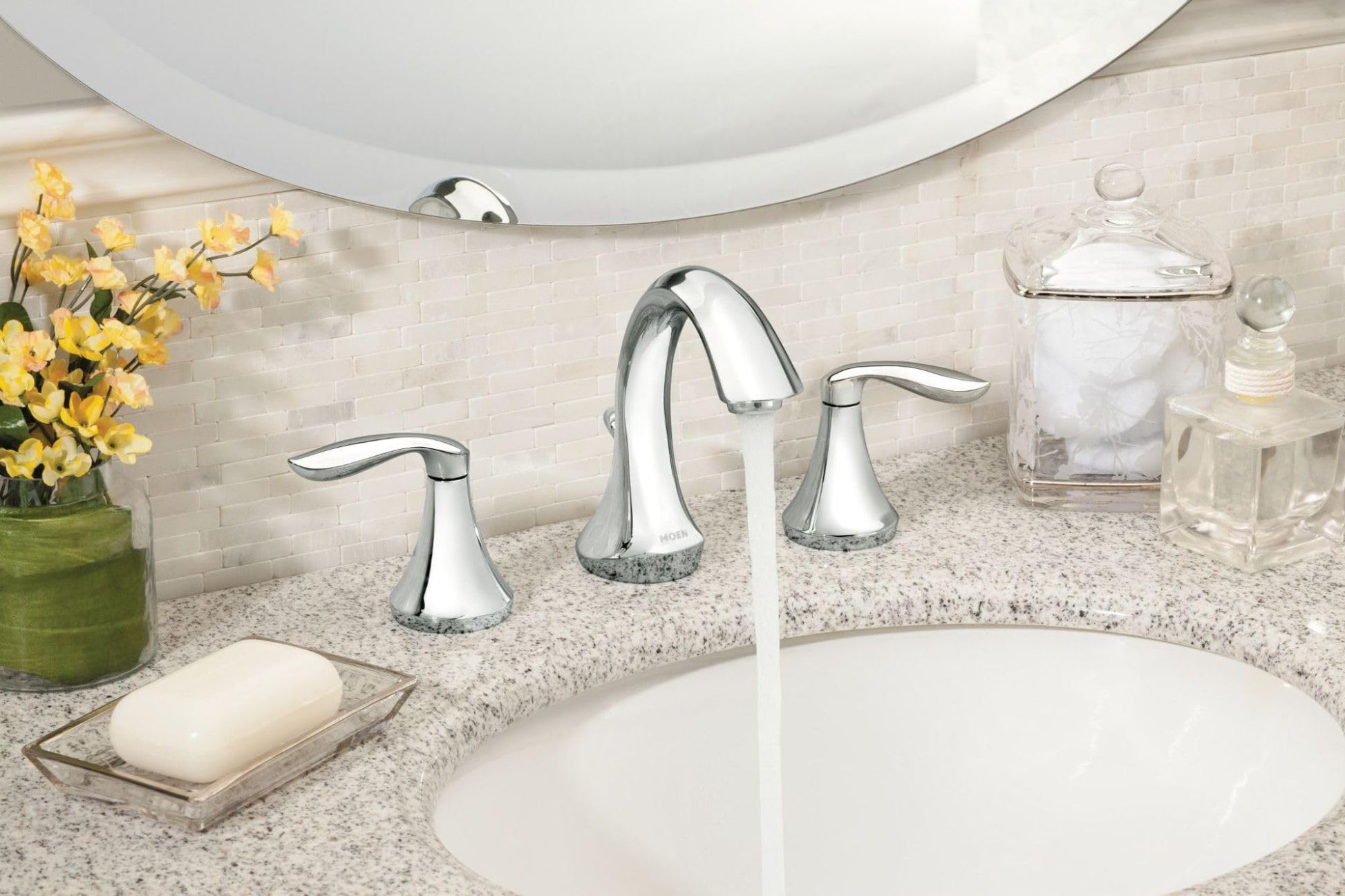 Chrome two-handle high arc bathroom faucet with curved spout installed on granite countertop above white sink.