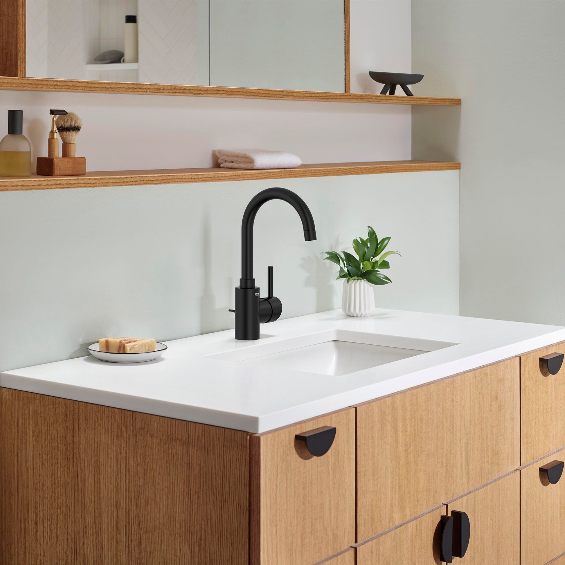 Matte black single-handle bathroom faucet with curved spout mounted on white countertop above wooden vanity.