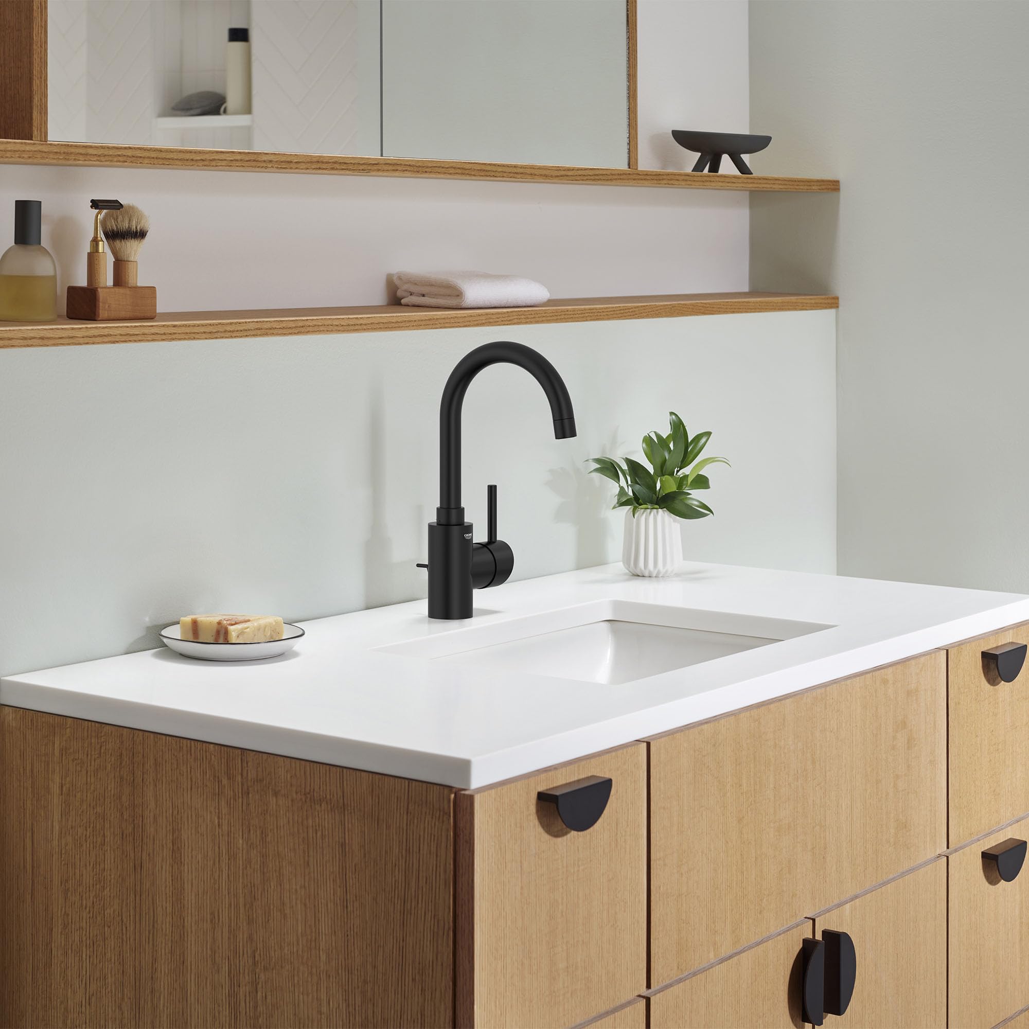Matte black single-handle bathroom faucet with curved spout mounted on white countertop above wooden vanity.