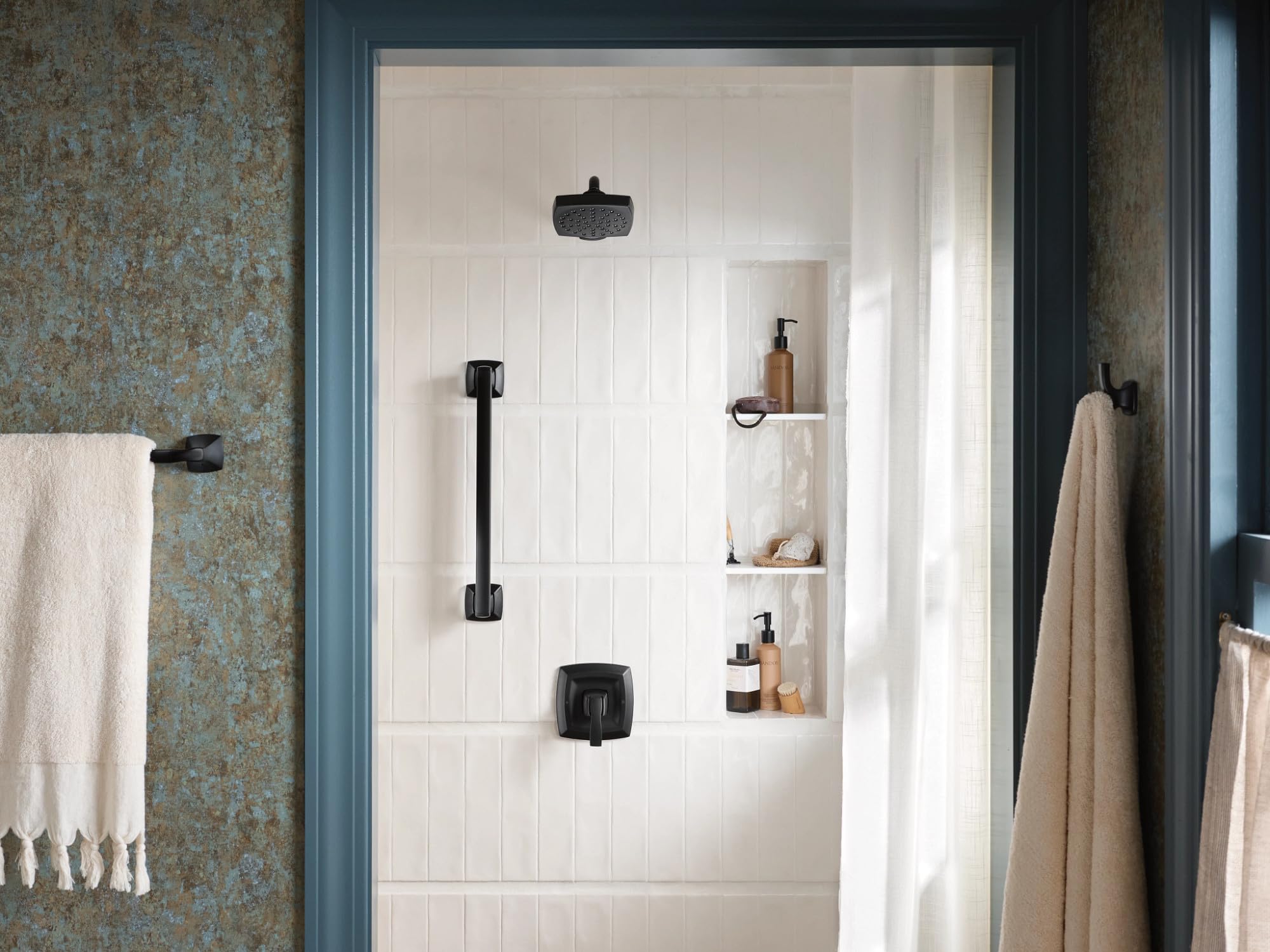 Matte black single-handle shower trim kit with showerhead, handheld sprayer, and control valve mounted on white subway tile w