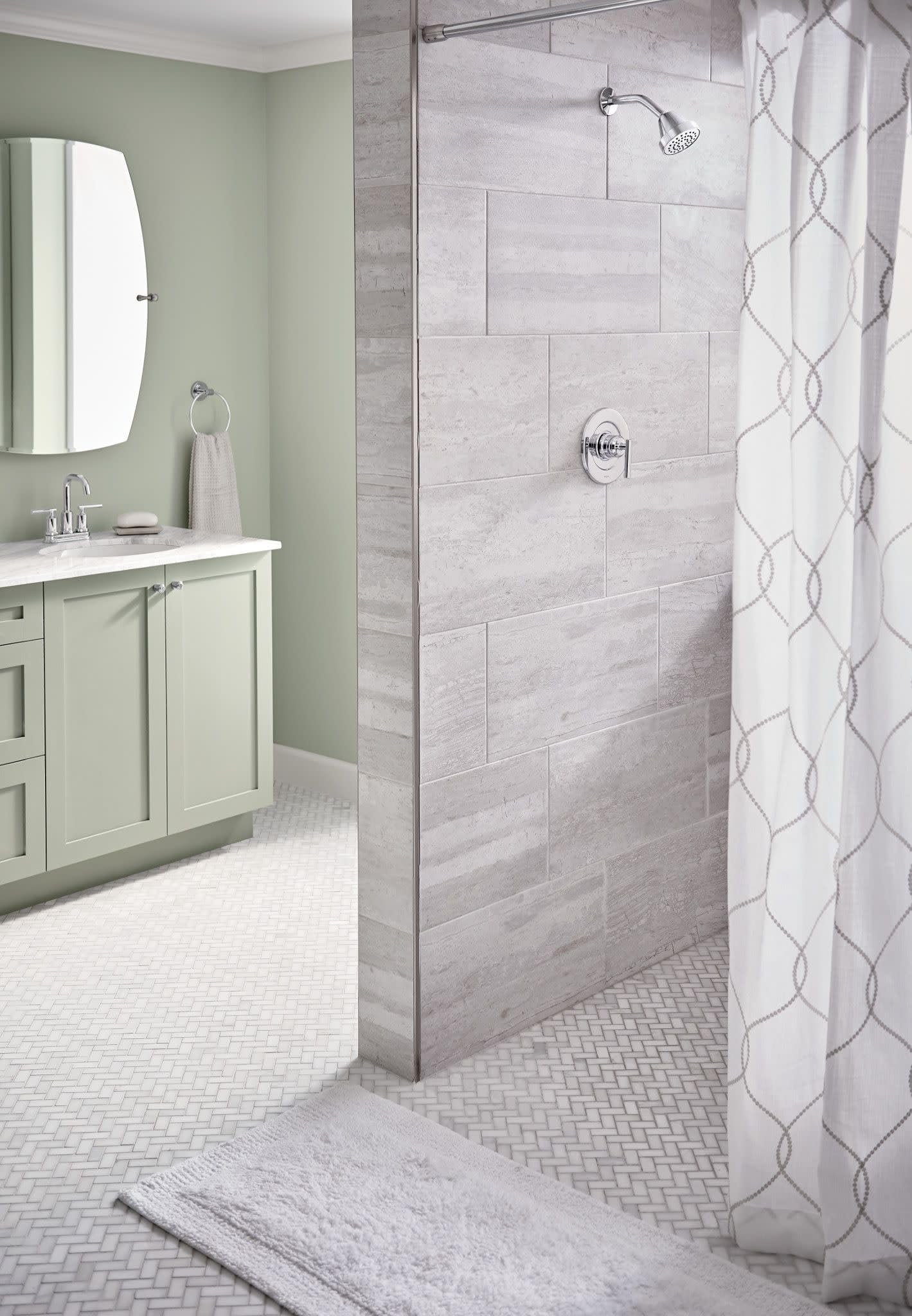 Chrome two-handle centerset faucet mounted on gray tile shower wall with overhead showerhead and valve controls.