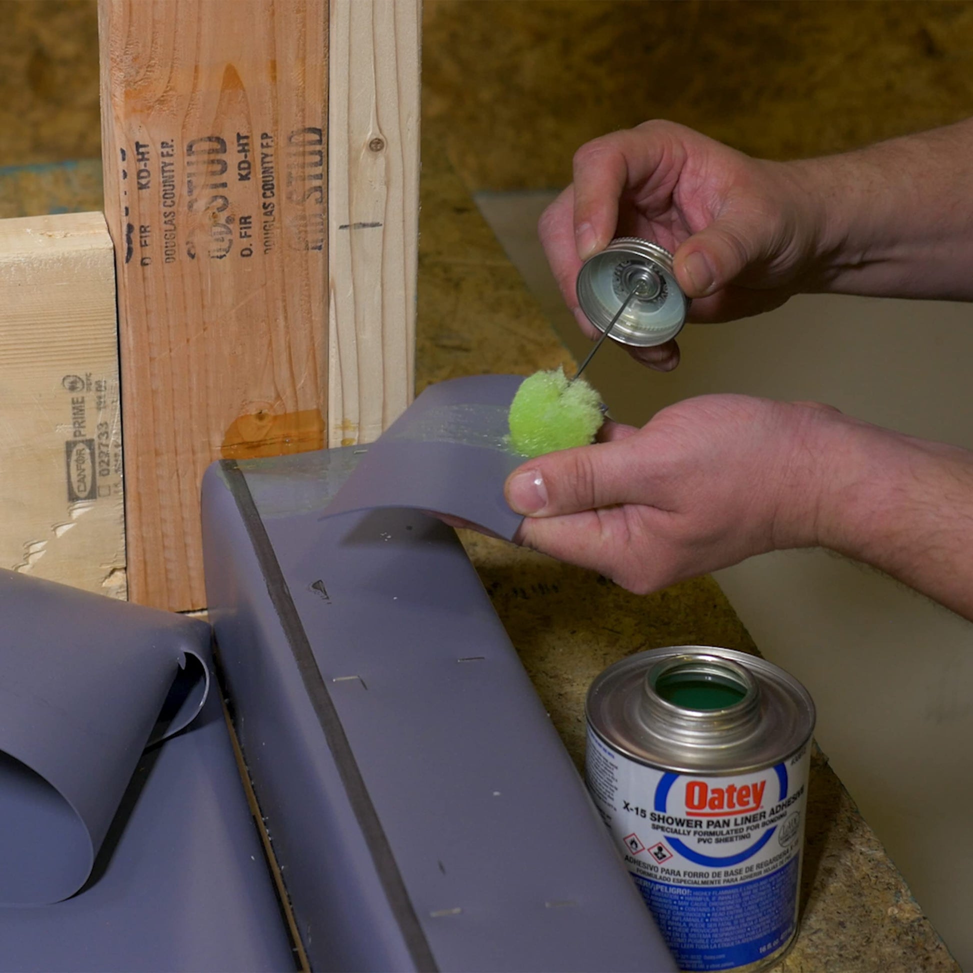 White PVC solvent cement being applied with brush applicator to plumbing pipe fitting during installation.