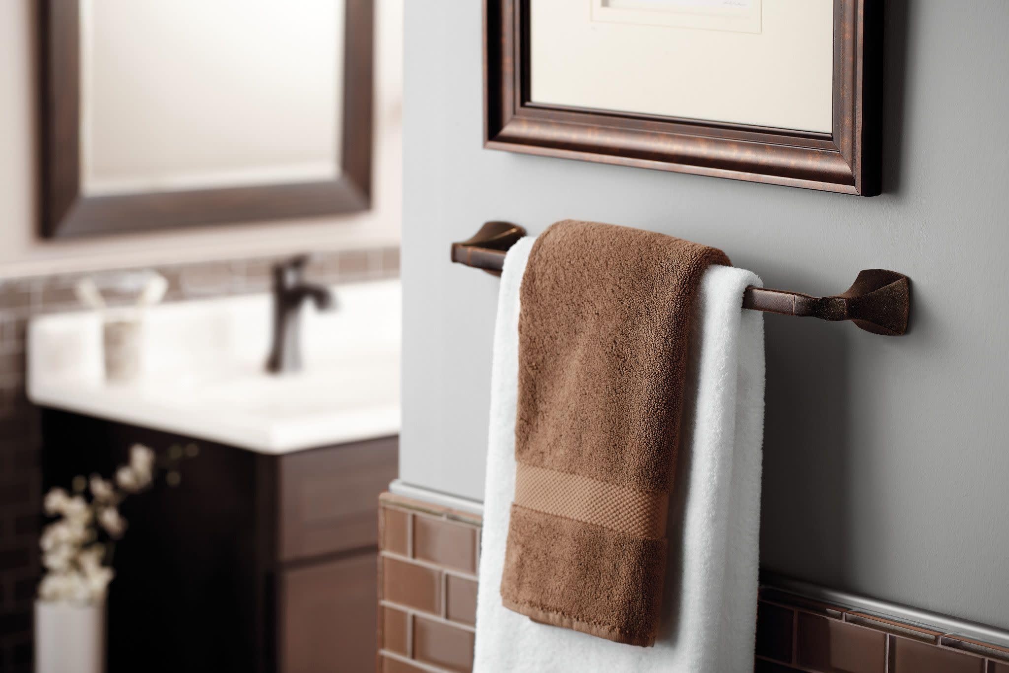 Bronze single-handle high-arc bathroom faucet mounted on white subway tile sink surround.
