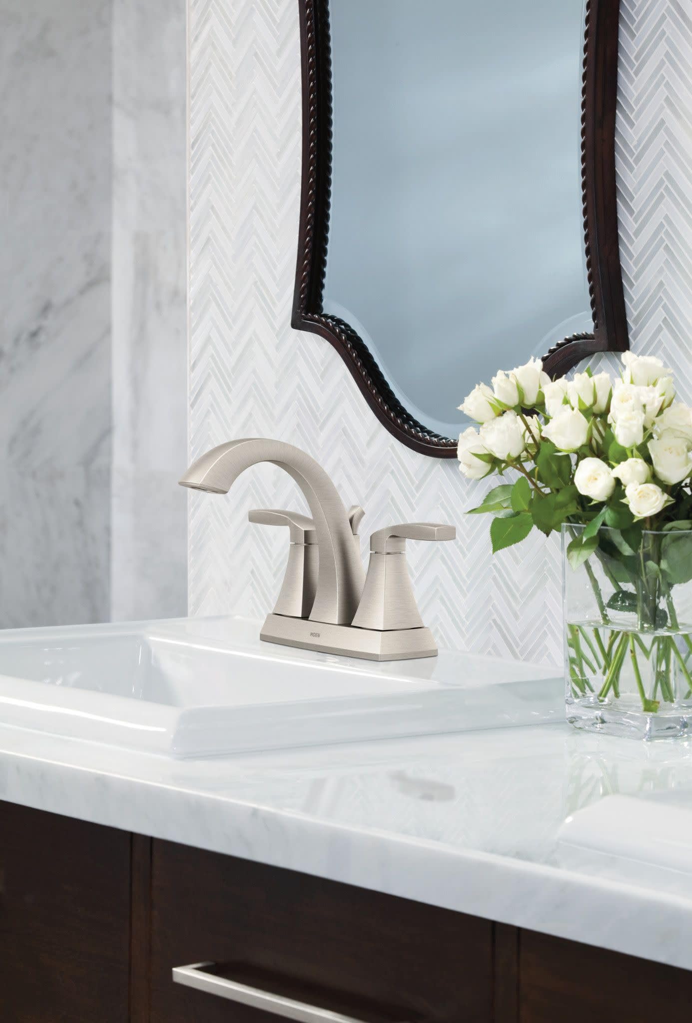 Brushed nickel two-handle high arc faucet with curved spout mounted on white bathroom sink counter.