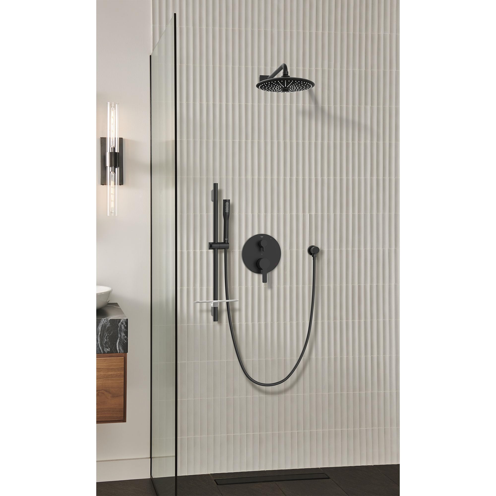 Matte black shower valve trim with round control handle, overhead rainfall showerhead, handheld wand, and diverter mounted on