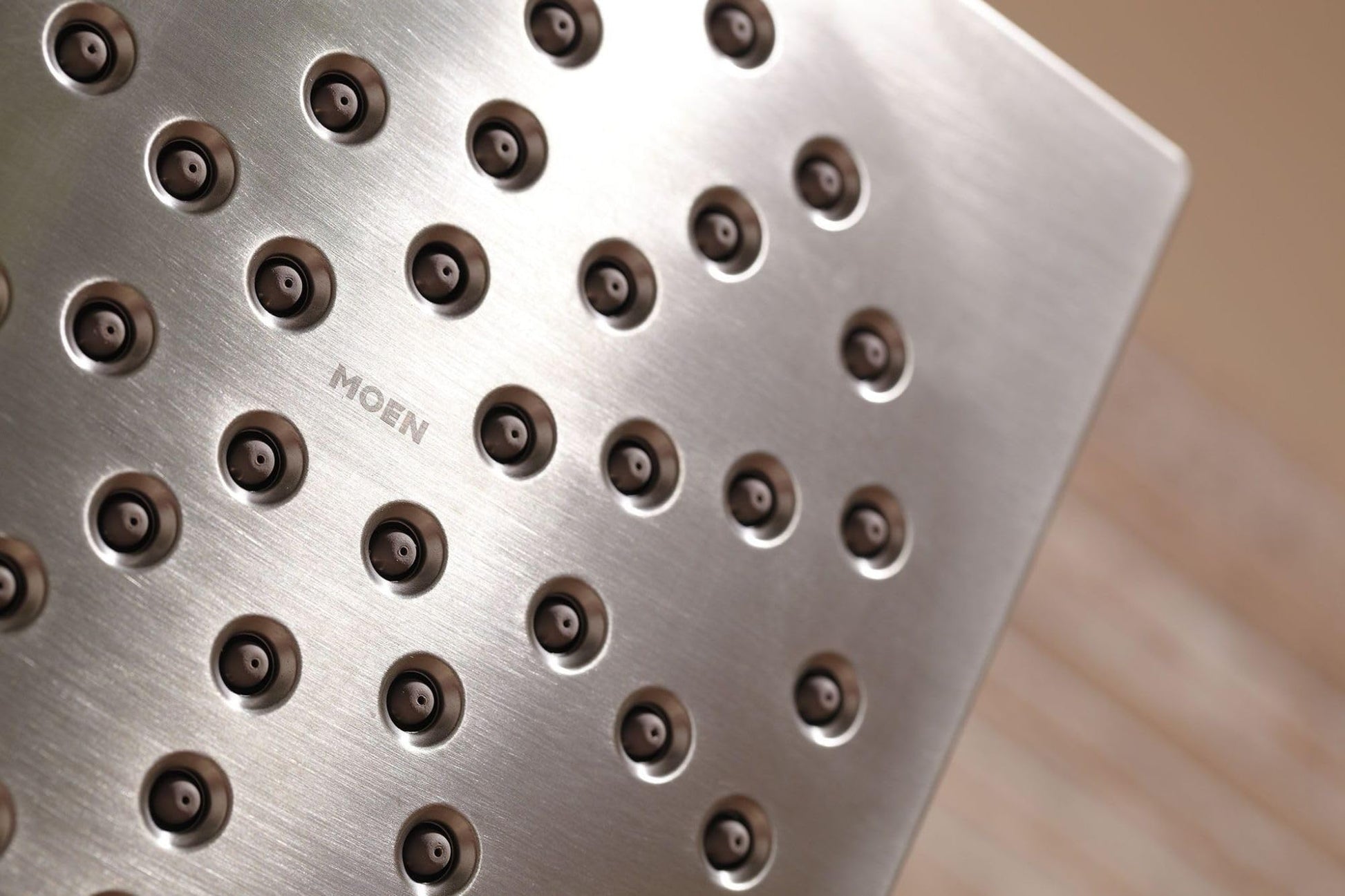 Brushed nickel square shower head with multiple spray jets and Moen branding visible.