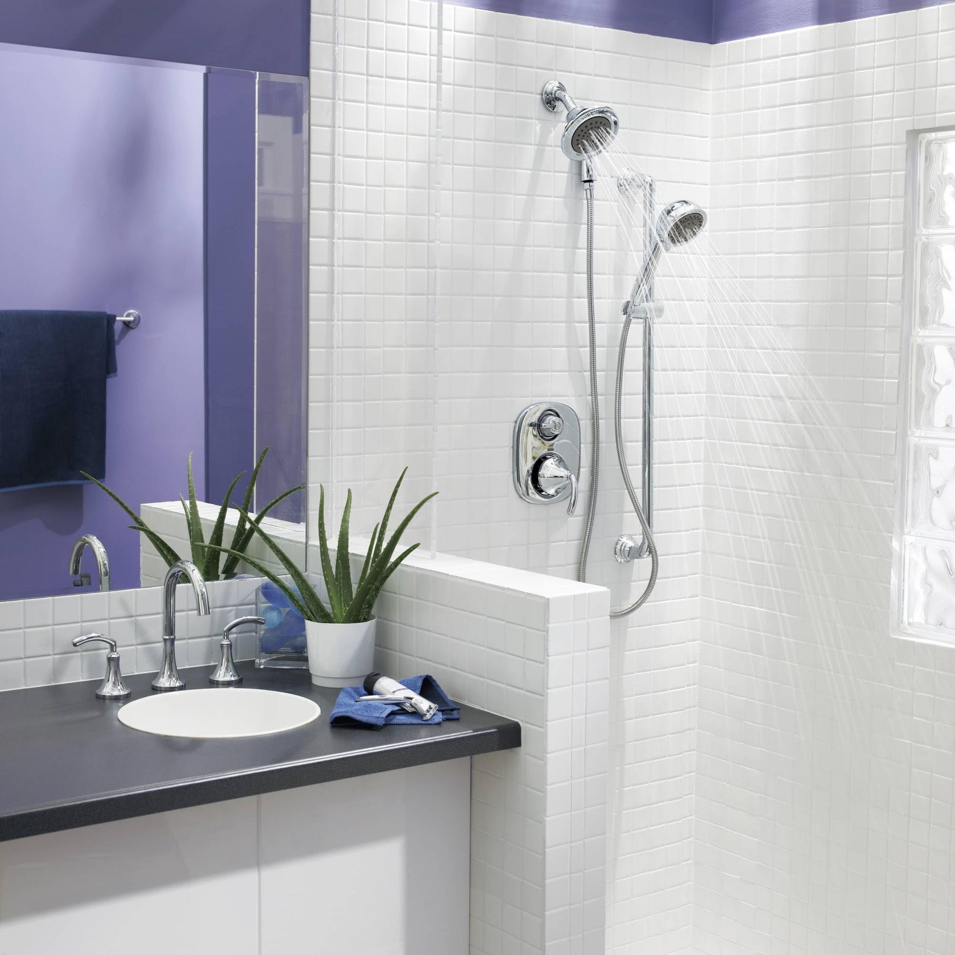 Polished nickel showerhead with handheld spray attachment mounted on white subway tile shower wall.