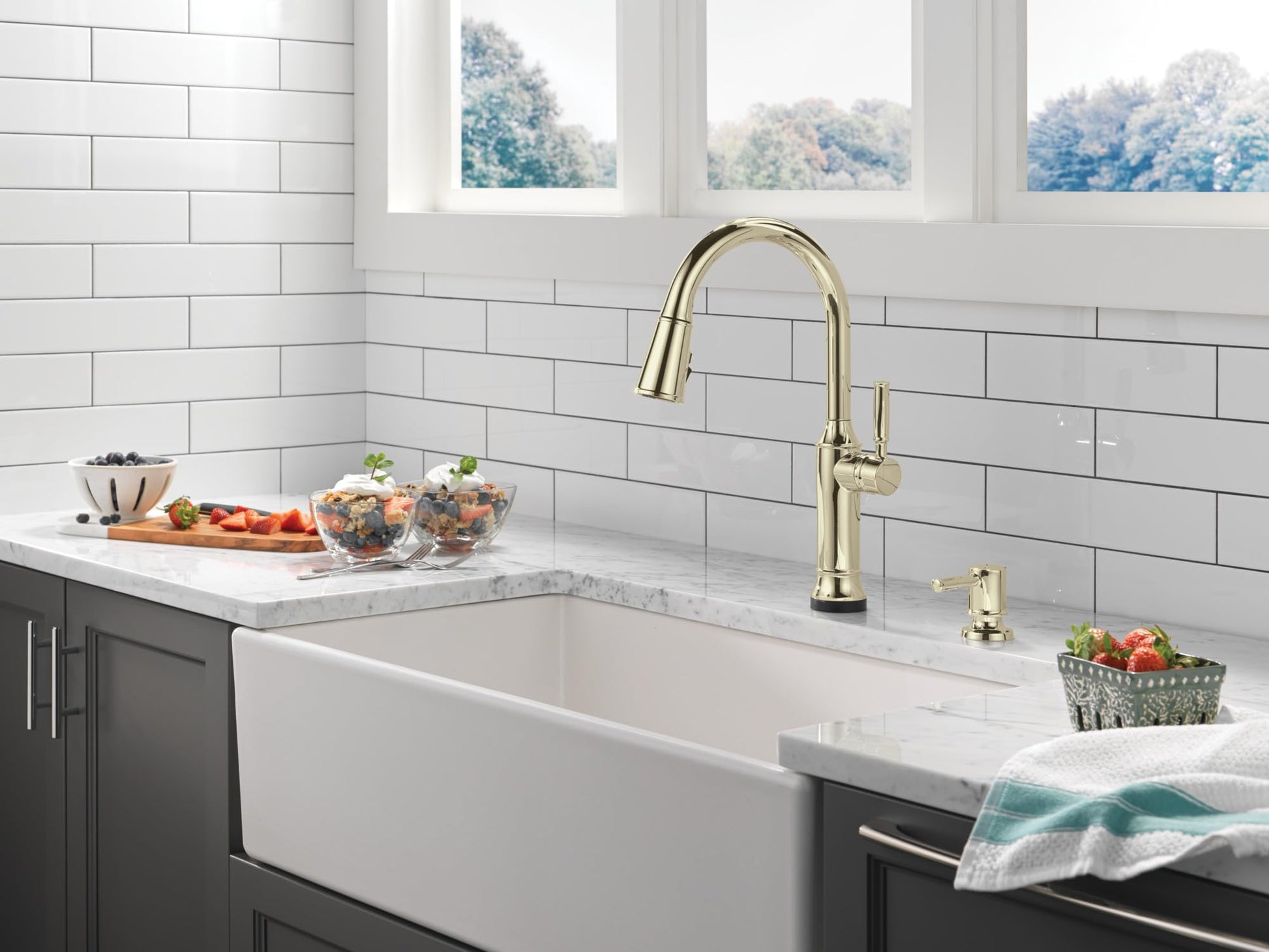 Polished nickel metal soap dispenser pump mounted on kitchen sink countertop next to faucet.