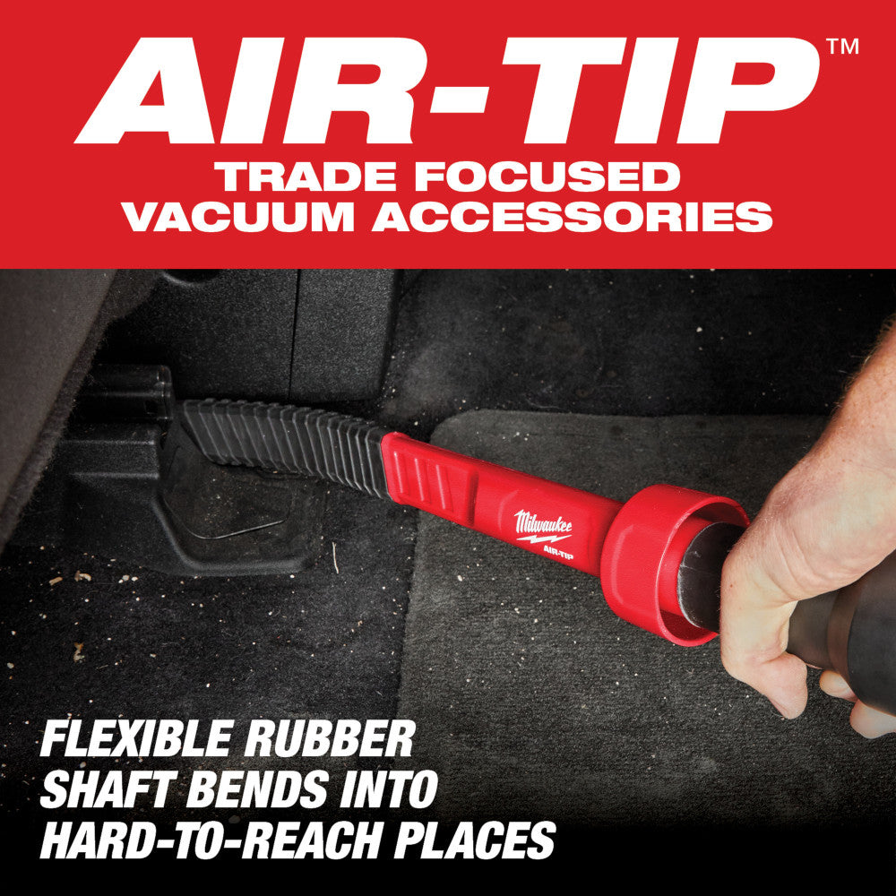 Red and black Milwaukee AIR-TIP vacuum attachment tool with flexible rubber shaft being used in vehicle interior.