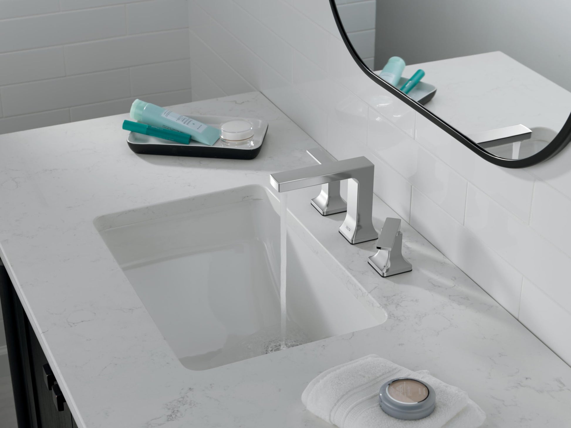 Chrome two-handle widespread bathroom faucet installed on white marble countertop above rectangular sink.