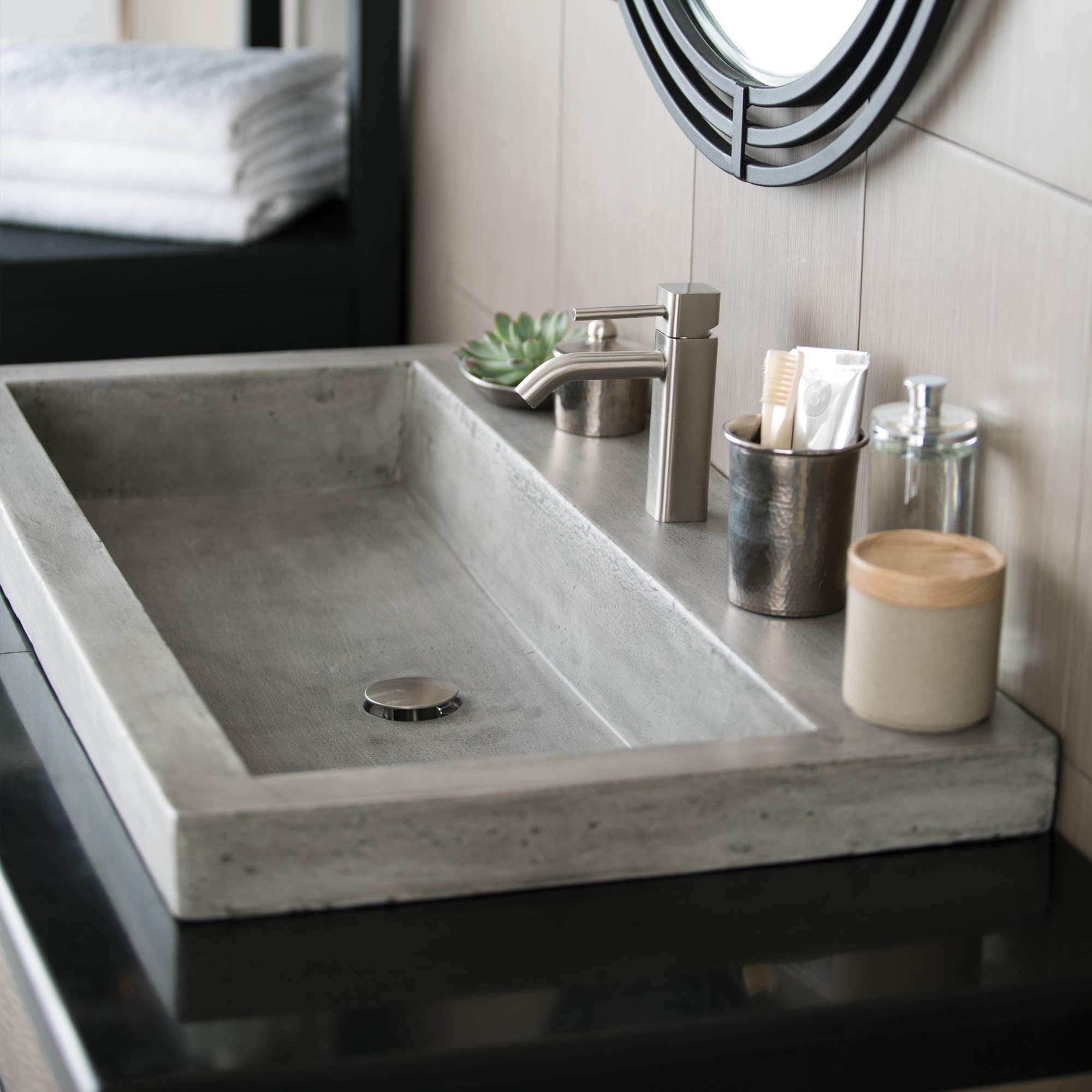 Rectangular concrete trough sink in light gray with single faucet hole and brushed nickel faucet installed on bathroom counte