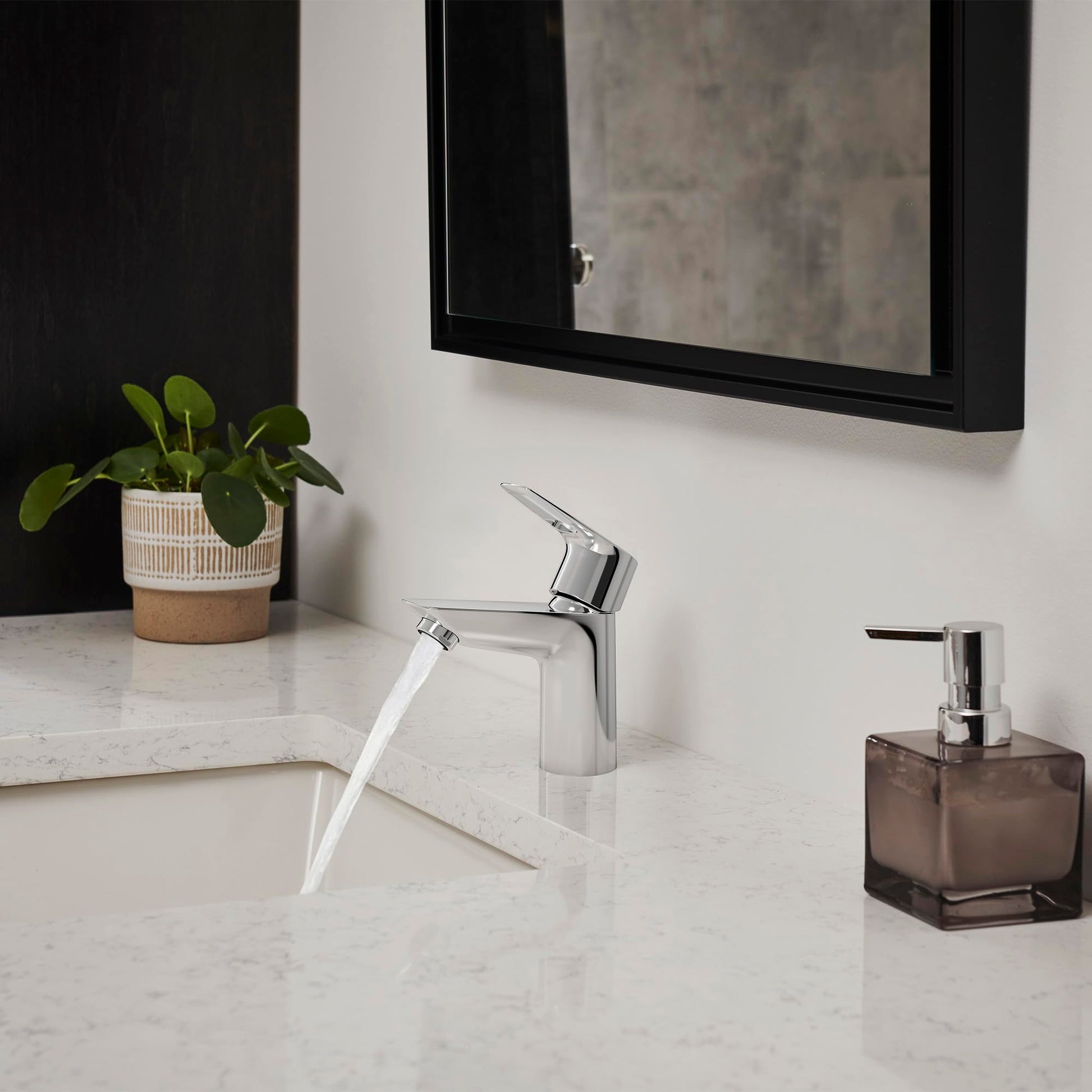 Chrome single-handle bathroom faucet with angled spout mounted on white marble countertop.