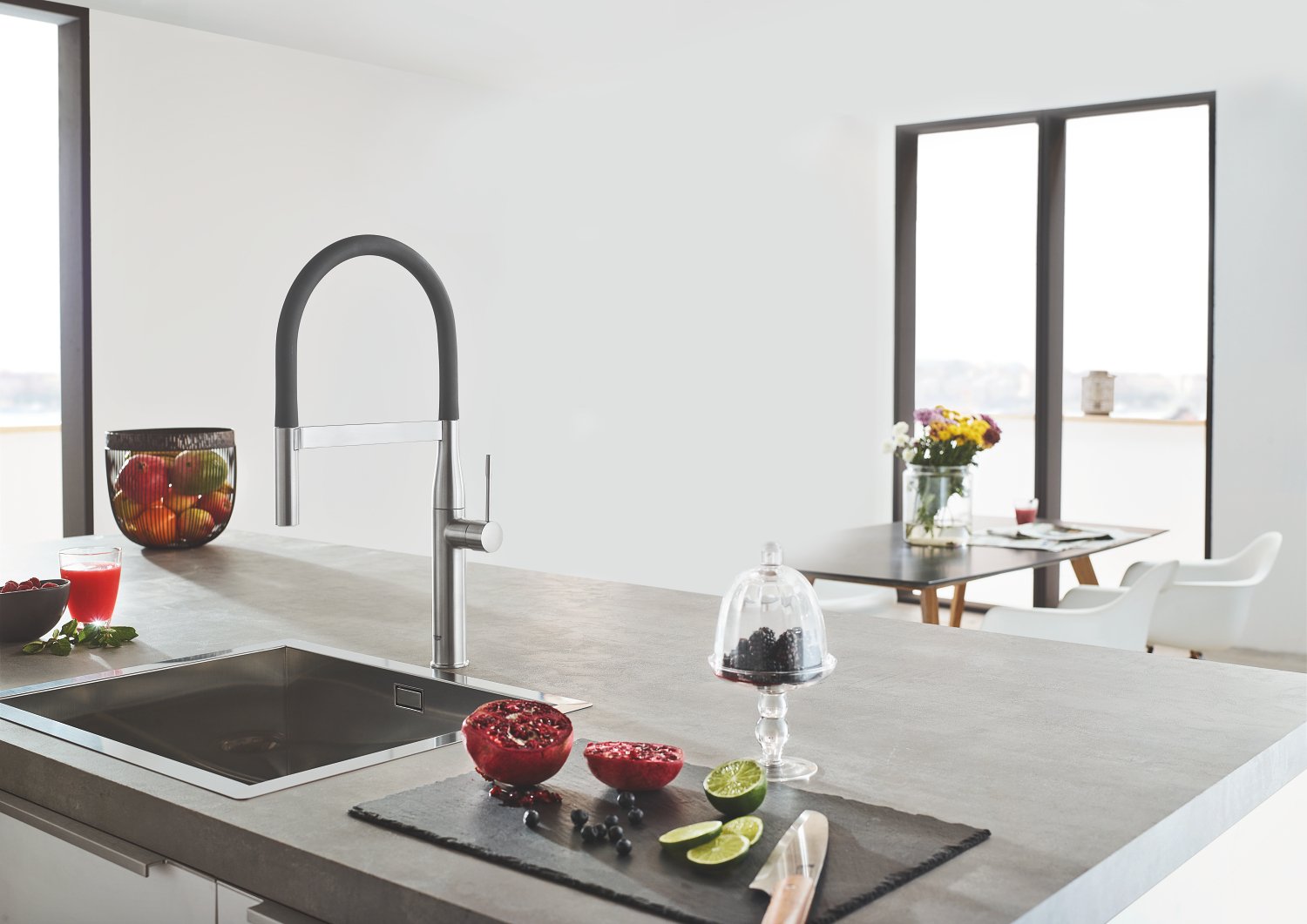 Matte dark grey kitchen faucet with curved pull-down spout installed above sink in modern kitchen.