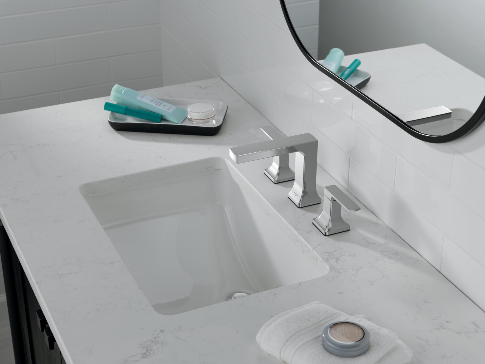 Chrome two-handle widespread bathroom faucet installed on marble countertop above white undermount sink.