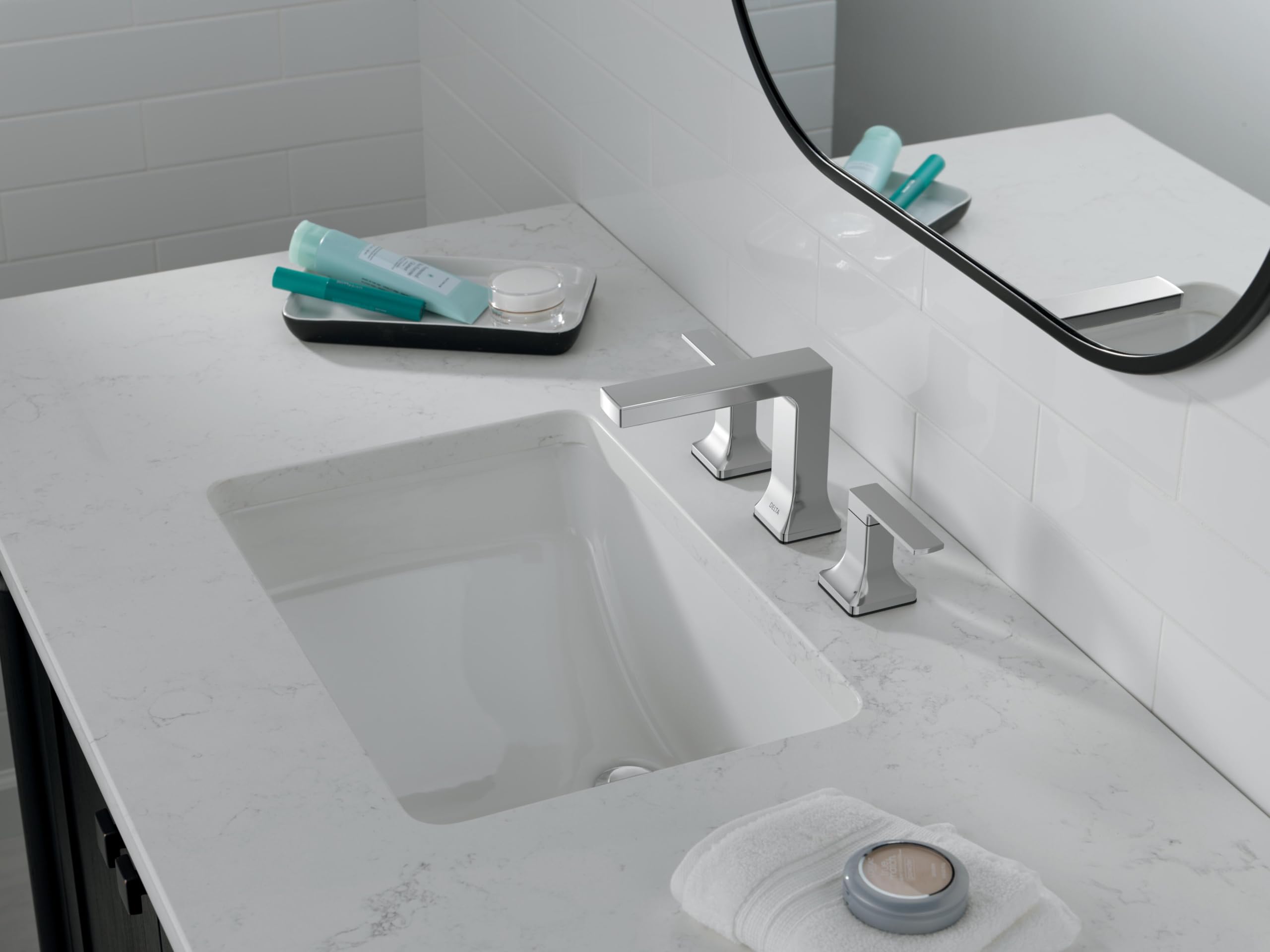 Chrome two-handle widespread bathroom faucet installed on marble countertop above white undermount sink.