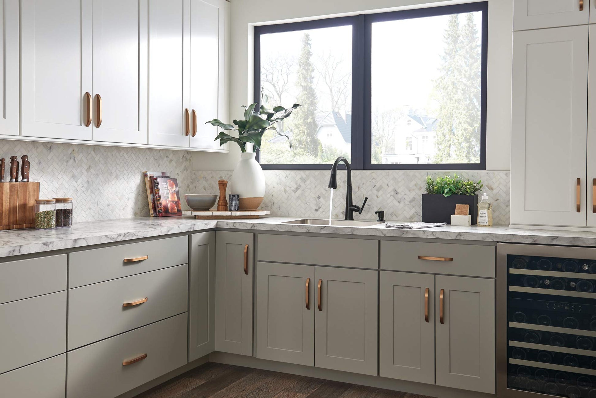 Matte black metal soap dispenser with cylindrical pump dispenser mounted on kitchen countertop near sink.
