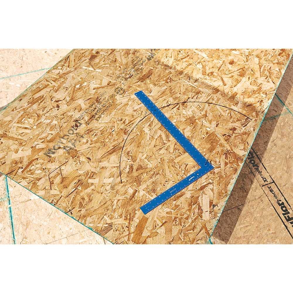 Blue framing square with laser-etched markings positioned on oriented strand board surface.