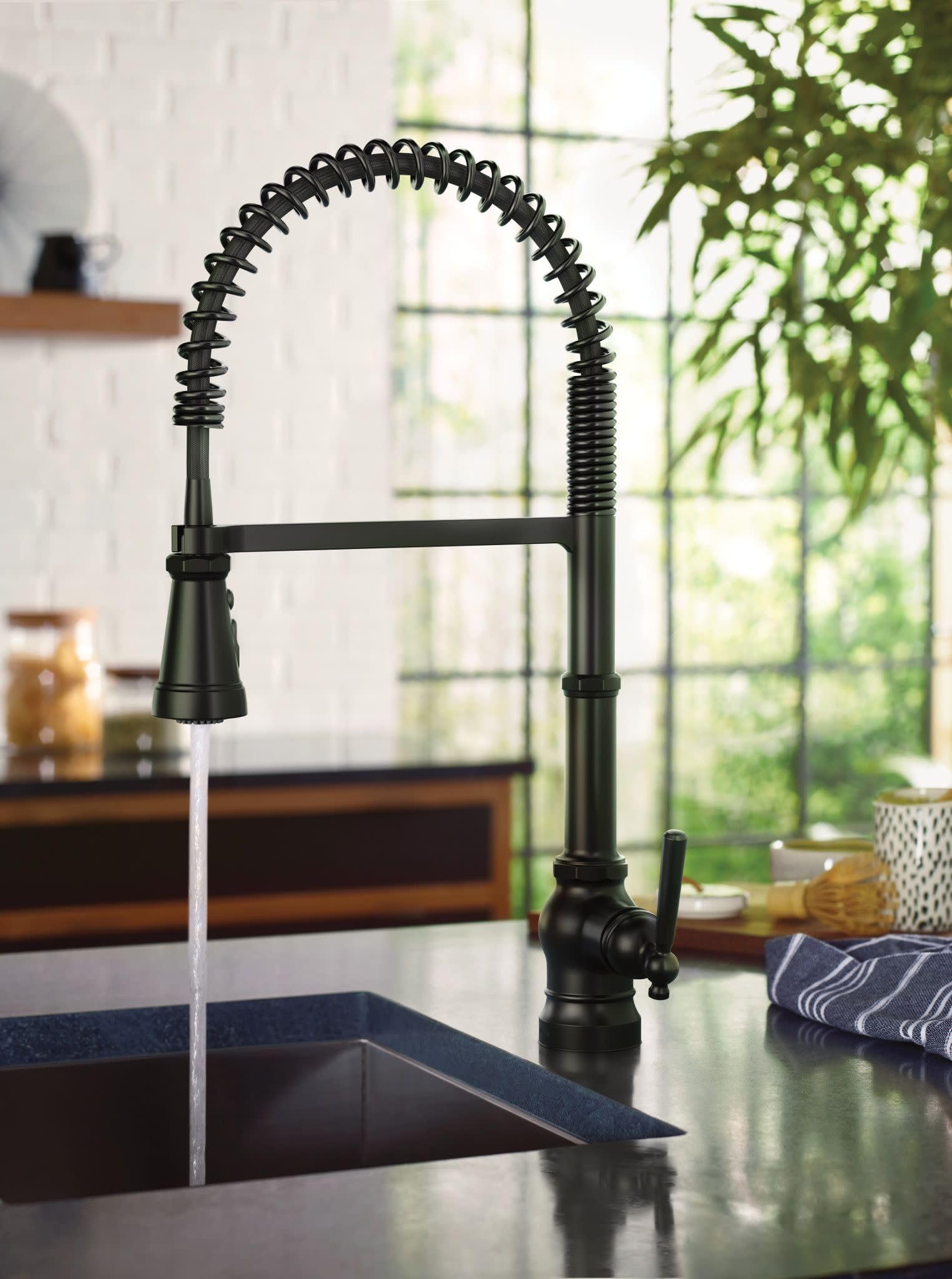 Matte black kitchen faucet with coiled pull-down sprayer and single handle mounted above sink.