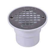 Black round shower drain strainer with grid pattern mounted on white PVC pipe fitting.