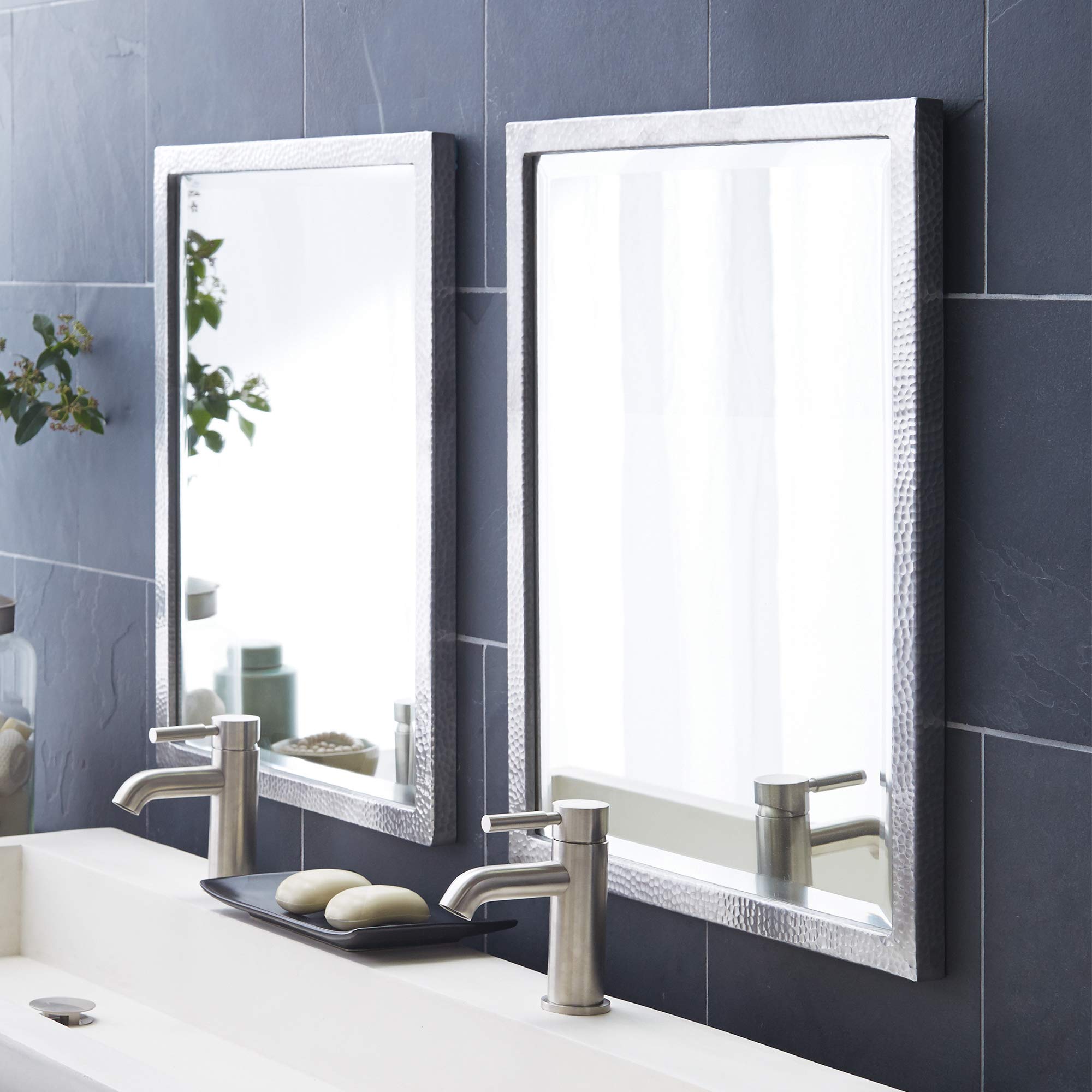 Two rectangular mirrors with white textured frames mounted on a bathroom wall above a sink.