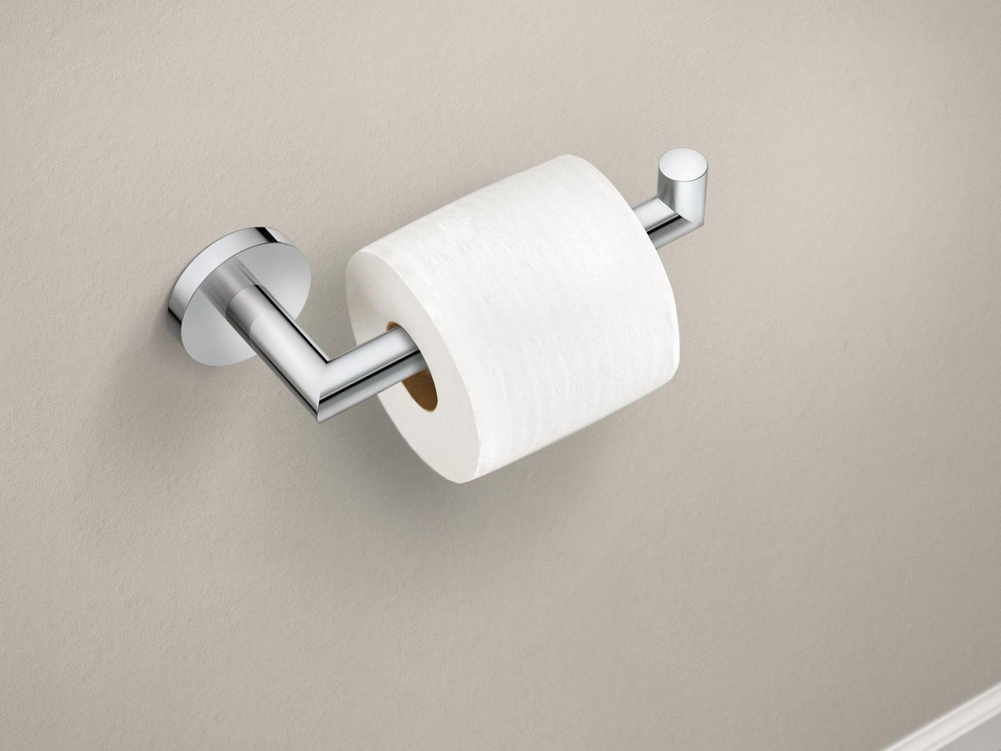 Chrome toilet paper holder with single post design holding a white roll on beige wall.