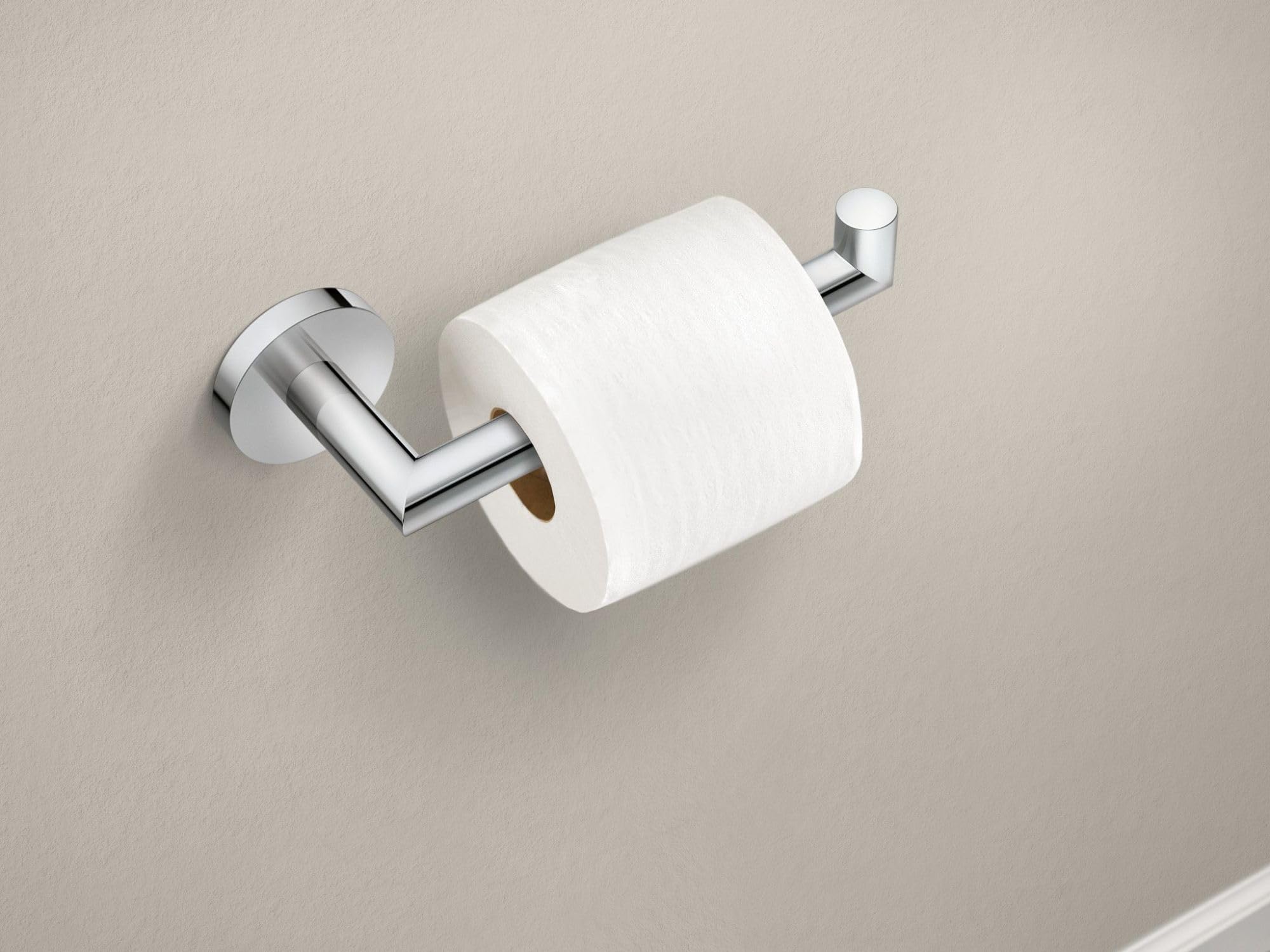 Chrome toilet paper holder with single post design holding a white roll on beige wall.