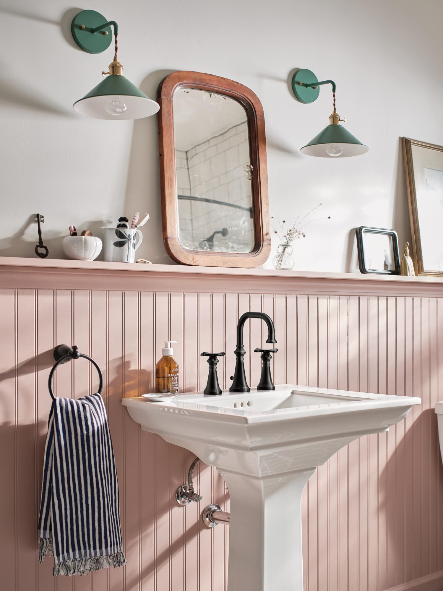 Matte black two-handle bathroom faucet with high arc spout and cross handles installed on white pedestal sink.