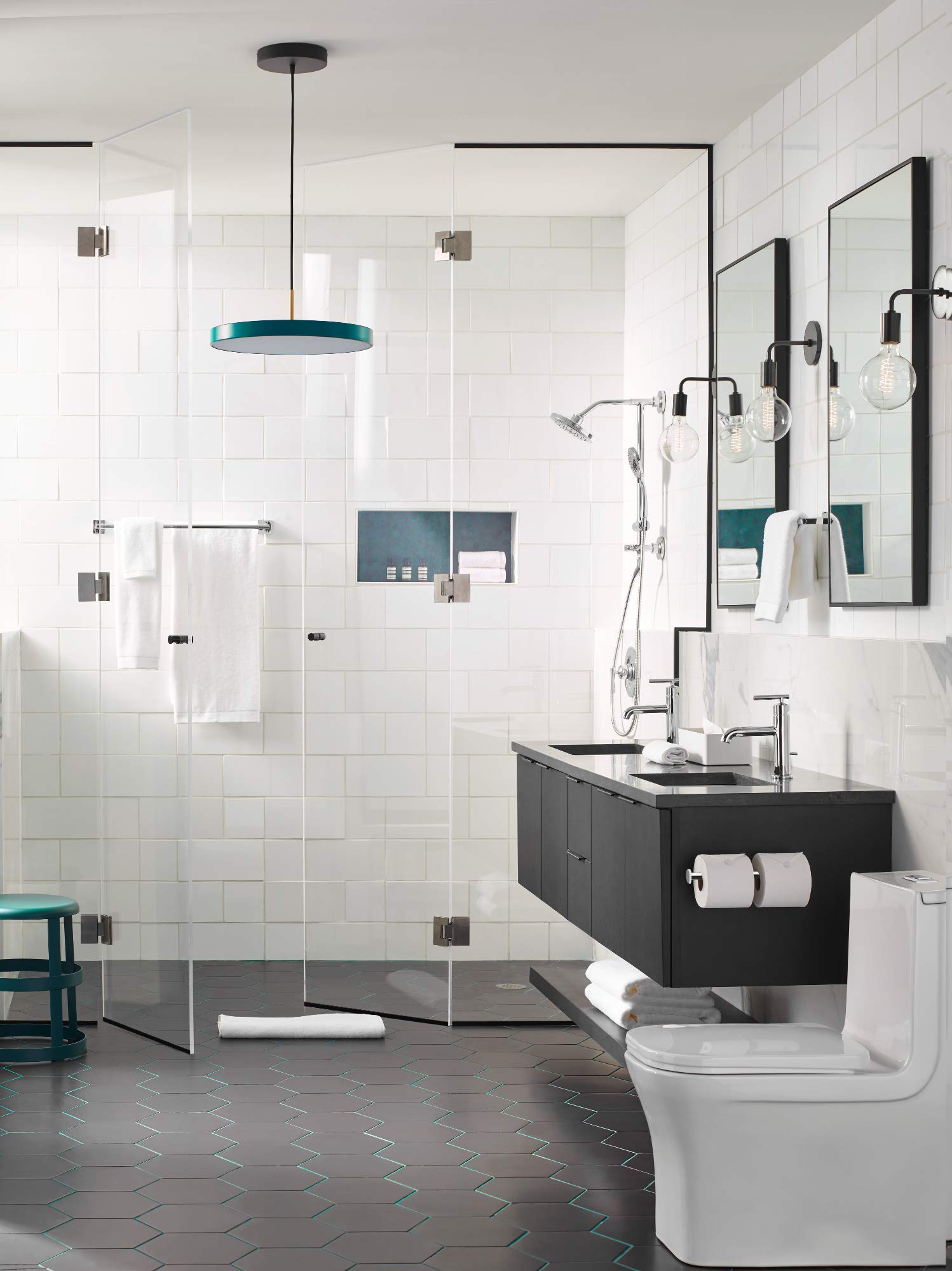 Chrome double post toilet paper holder mounted on black bathroom vanity beside sink.