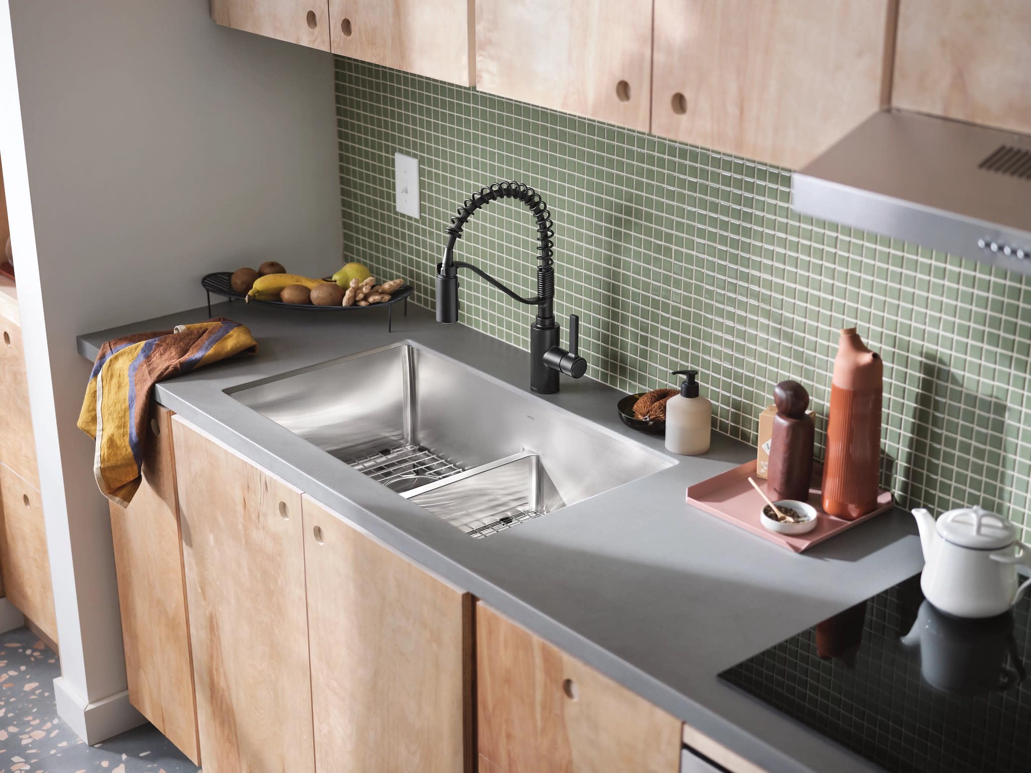 Matte black spring kitchen faucet with single handle mounted above stainless steel dual basin sink.