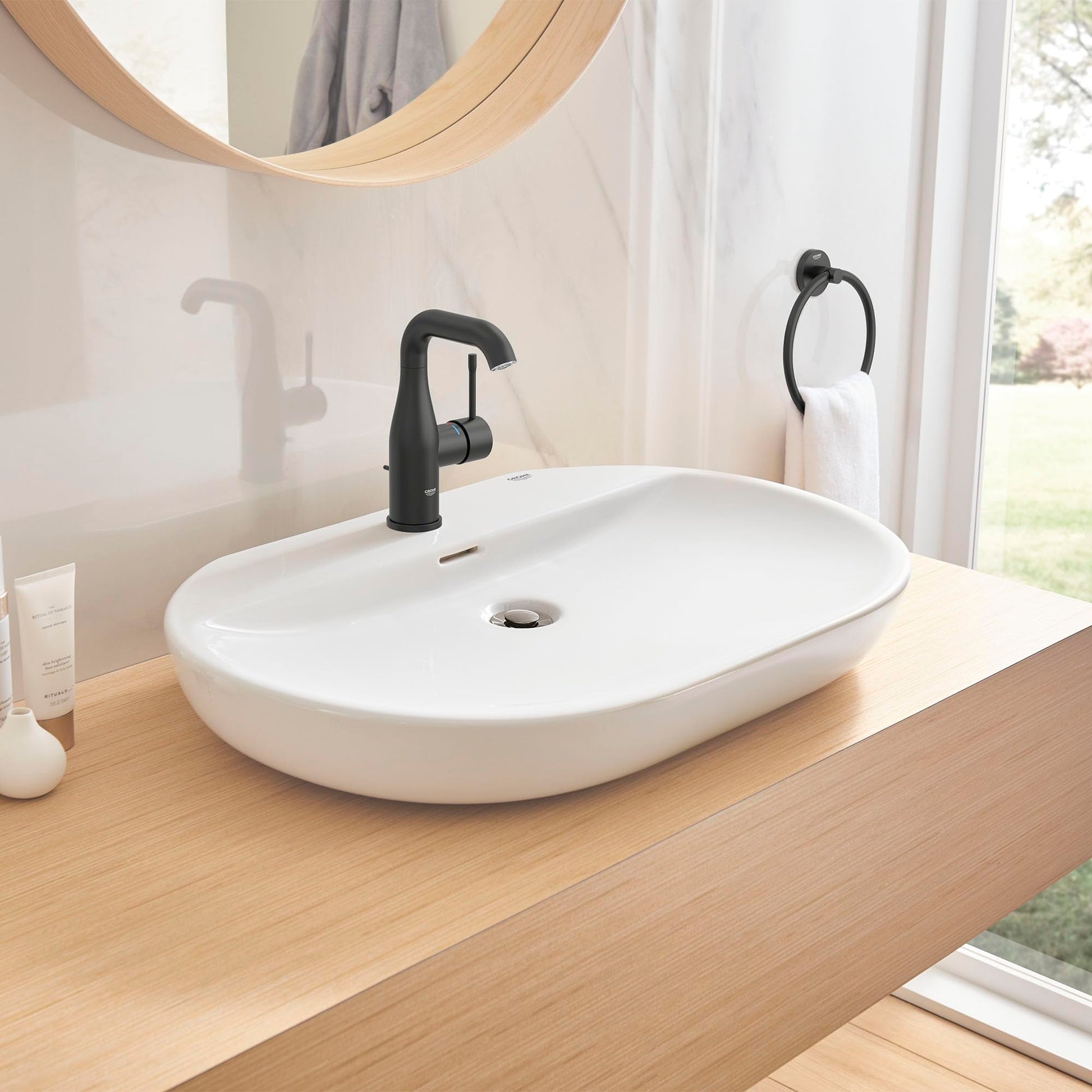 Matte black single-handle bathroom faucet with curved spout mounted on white oval sink.