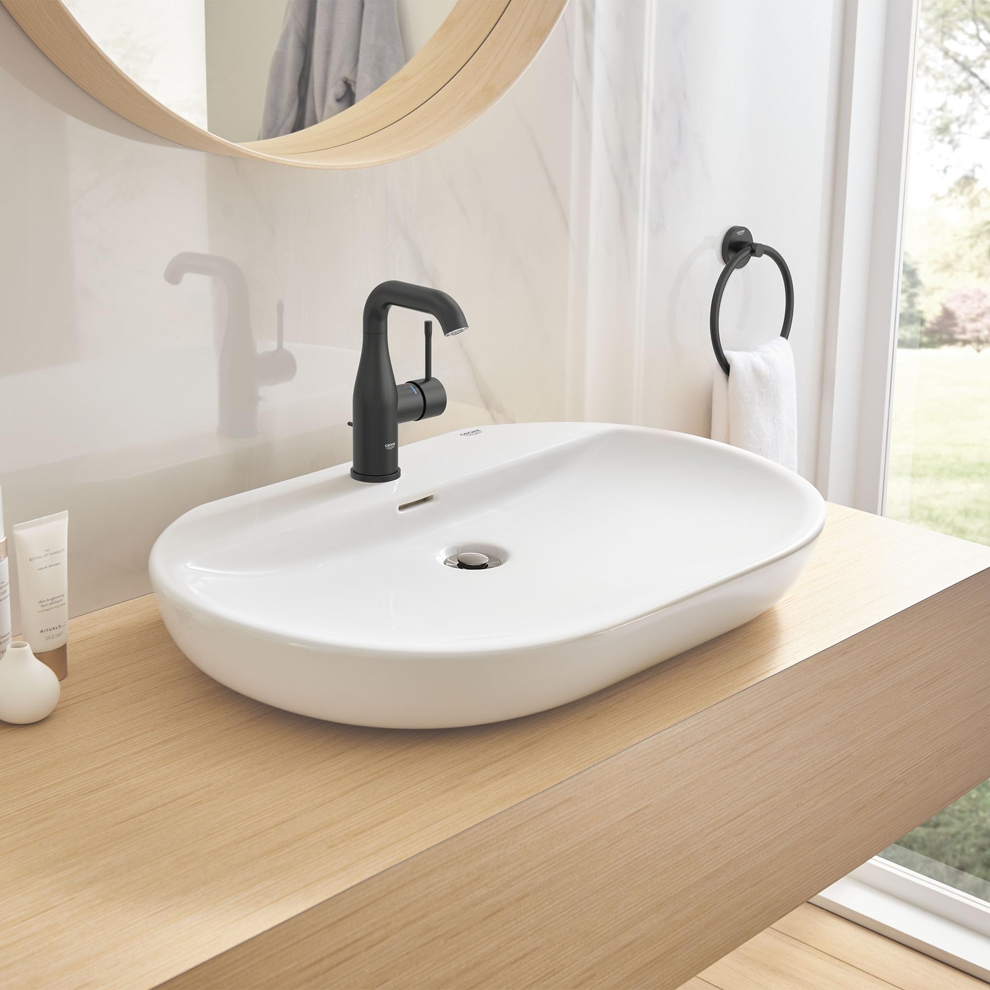 Matte black single-handle bathroom faucet with curved spout mounted on white oval sink.