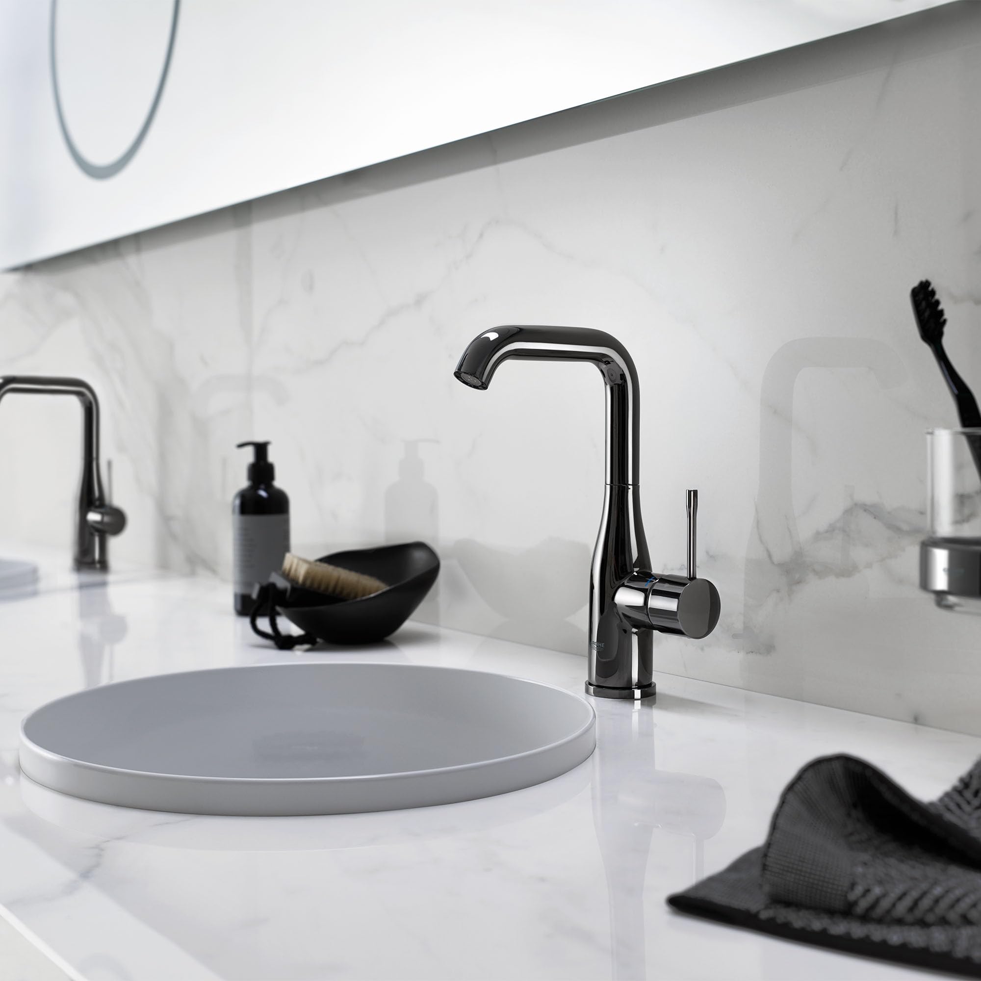Grohe Essence single-handle bathroom faucet in hard graphite with curved spout mounted above round vessel sink.