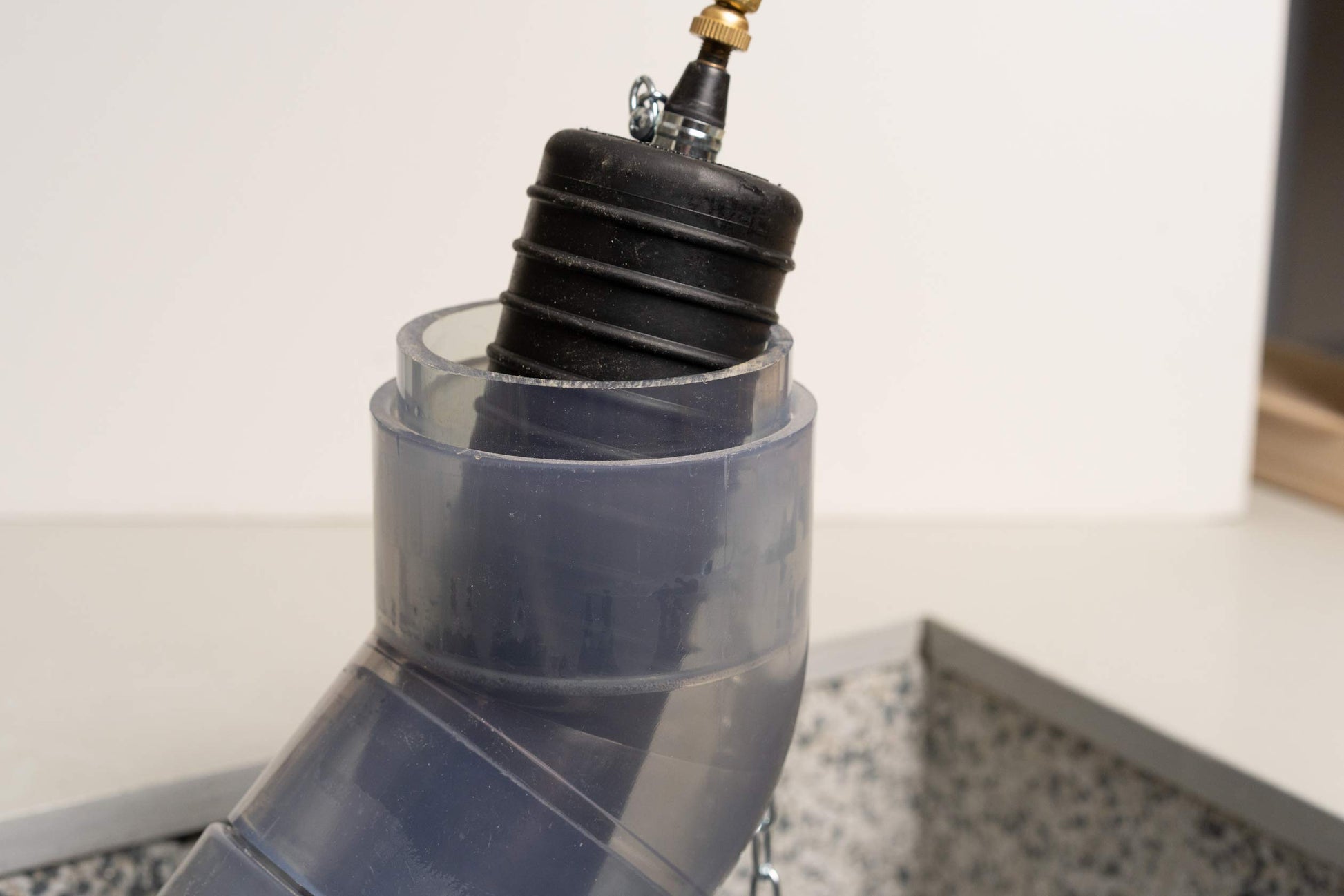 Black inflatable test plug with brass valve and clear plastic housing adapter.