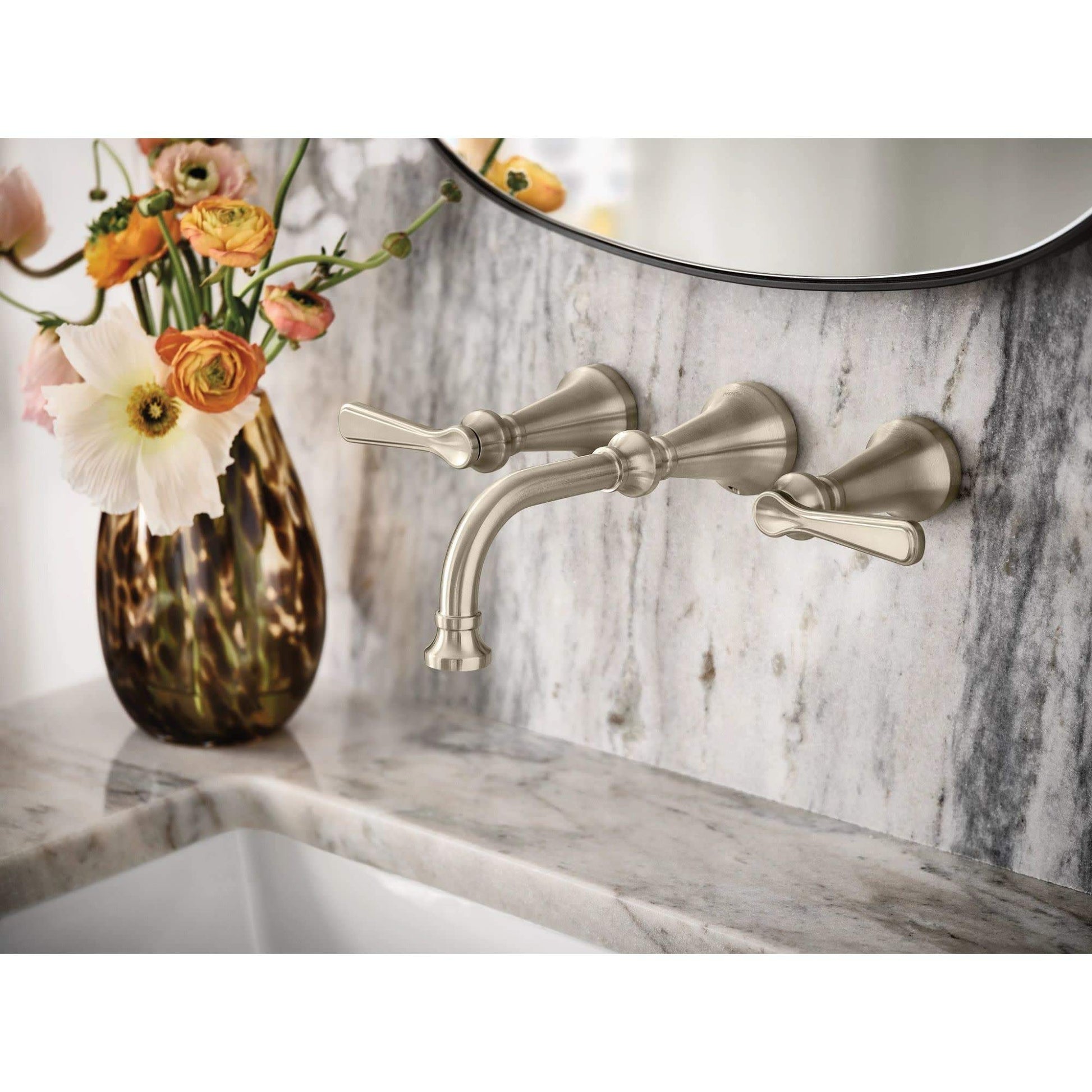 Matte black wall-mount bathroom faucet with lever handles and curved spout installed above marble sink.