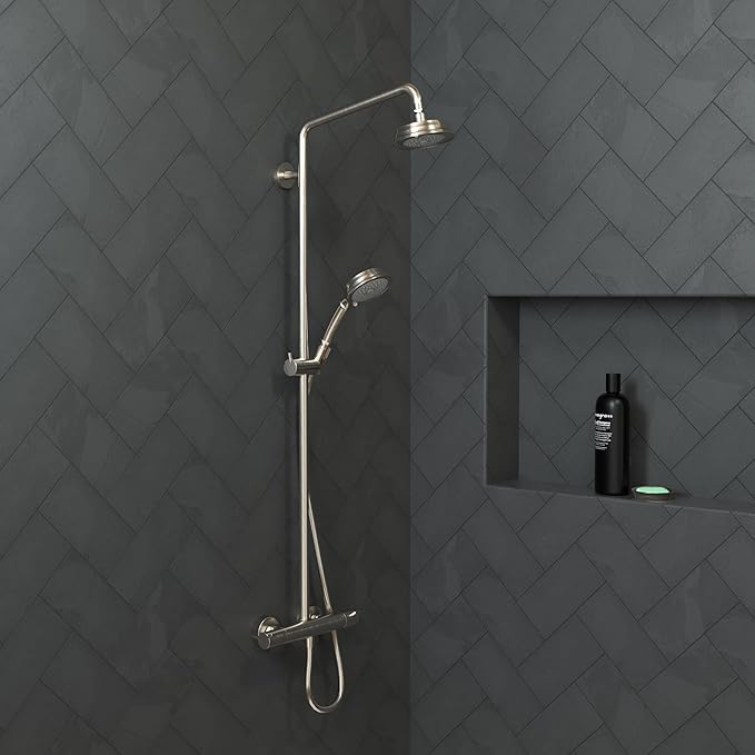 Brushed nickel shower system with overhead rainfall head, handheld wand, and wall-mounted controls installed on dark tile.