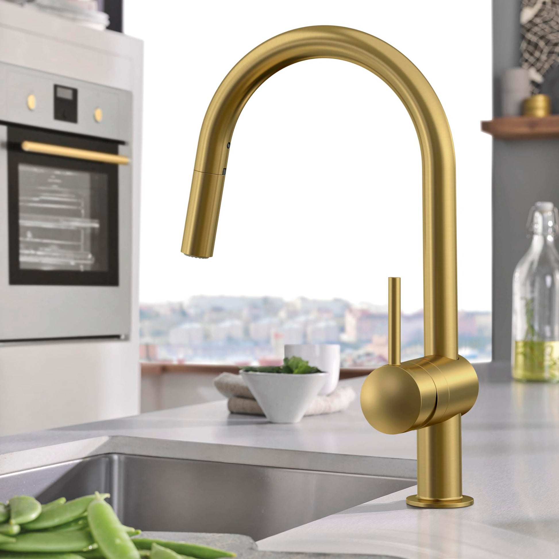 Single-handle pull-down kitchen faucet with curved spout in brushed gold finish over stainless steel sink.