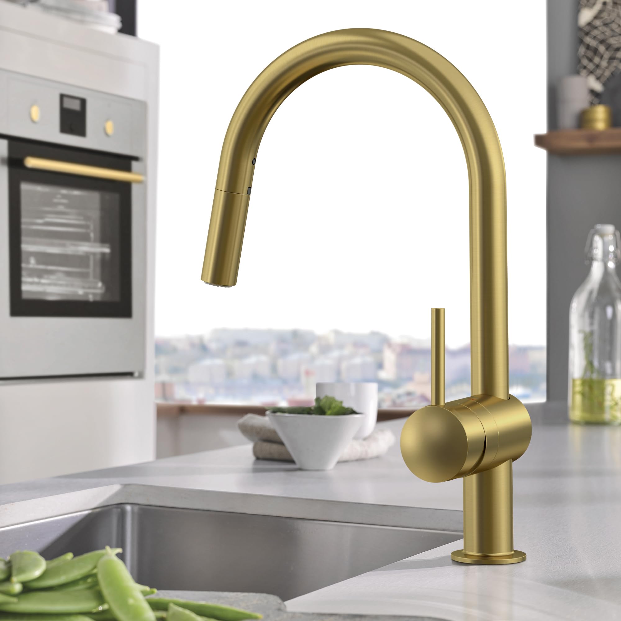 Single-handle pull-down kitchen faucet with curved spout in brushed gold finish over stainless steel sink.